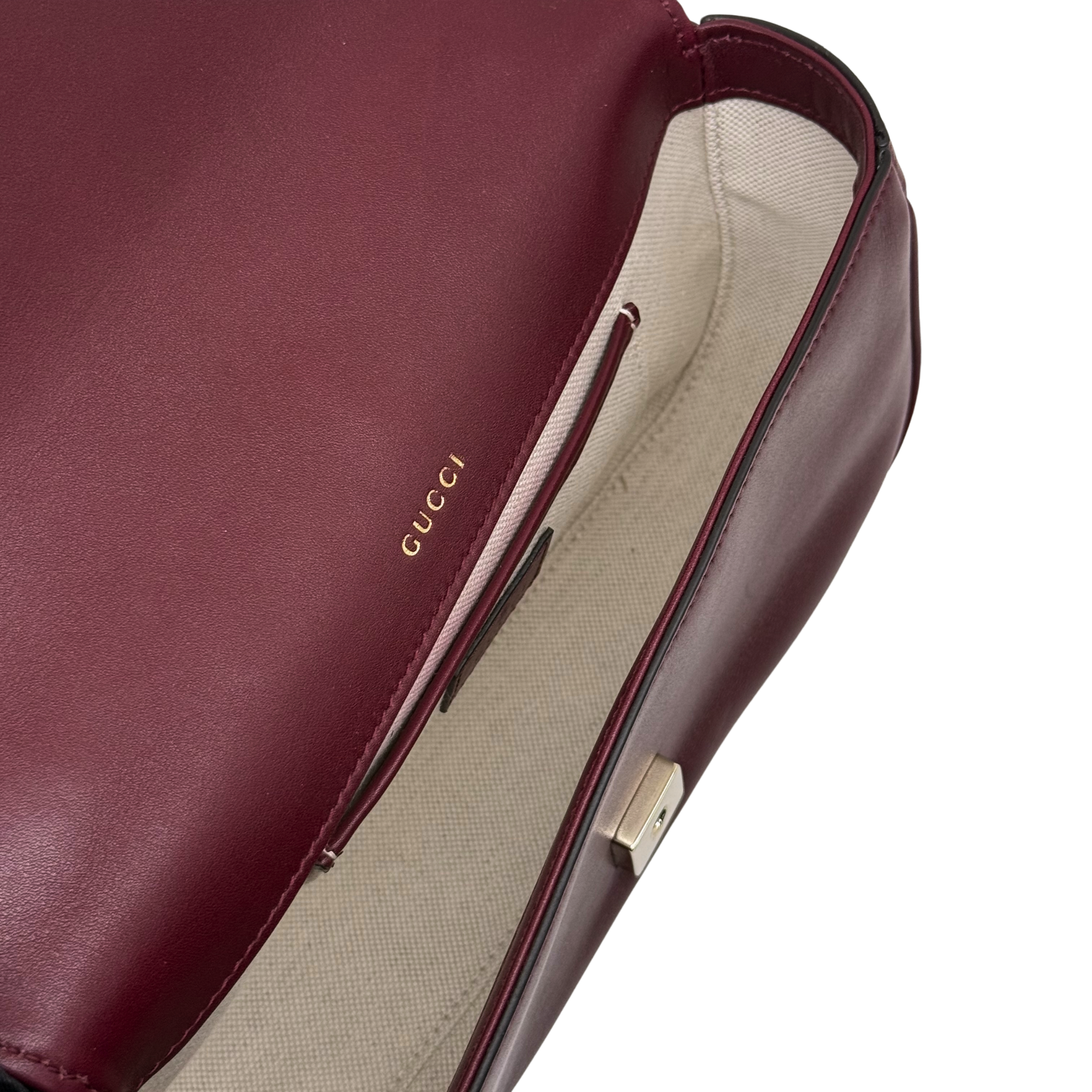 Gucci maroon leather flap bag close-up, fabric-lined interior and zipper pull