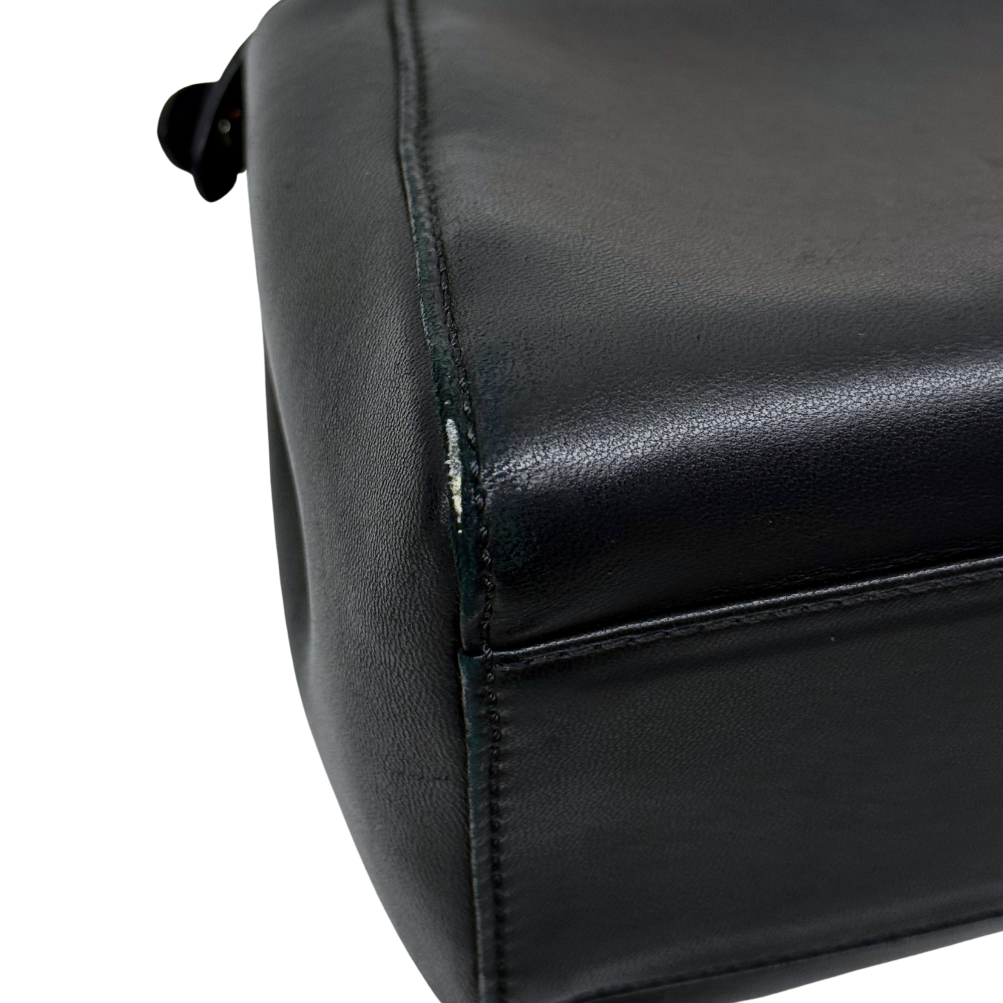 Close-up of black leather handbag corner with visible stitching