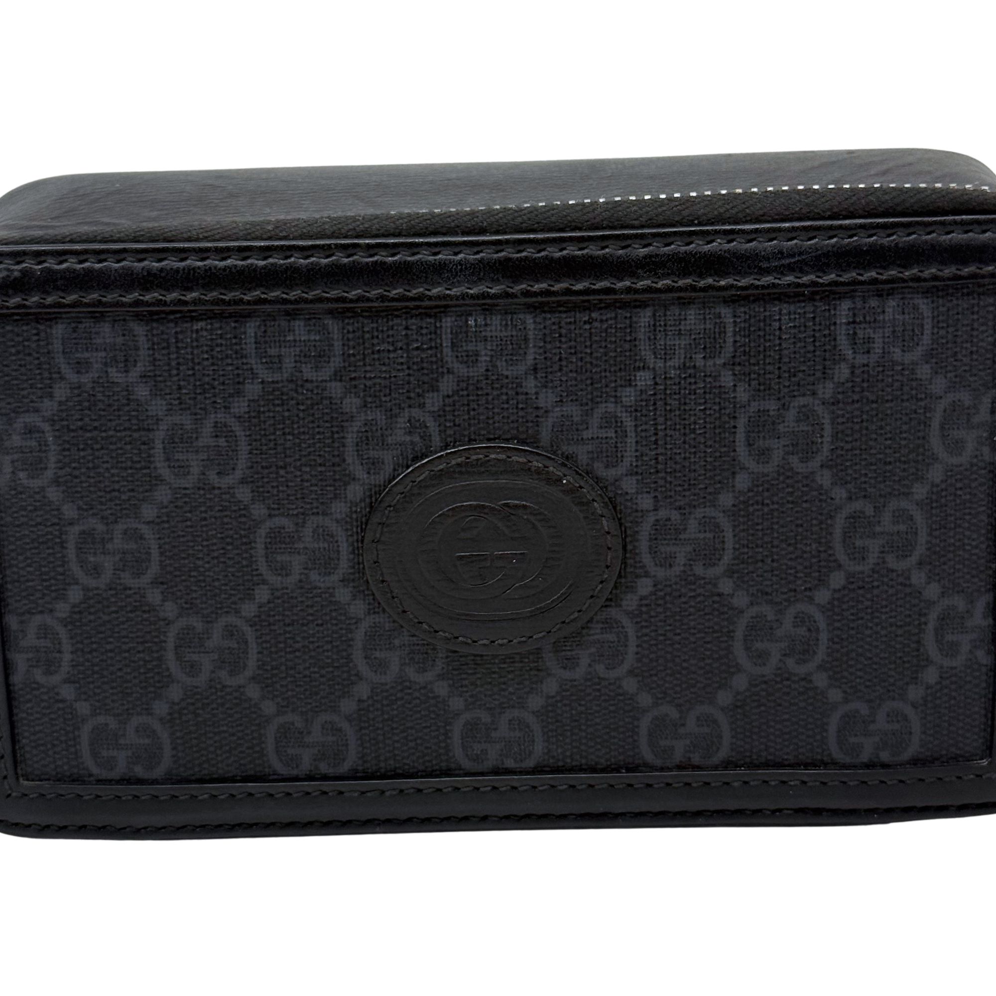 Small crossbody bag front close-up, dark GG monogram canvas with round logo patch