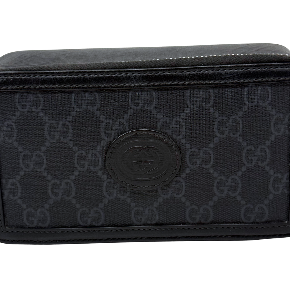 Small crossbody bag front close-up, dark GG monogram canvas with round logo patch