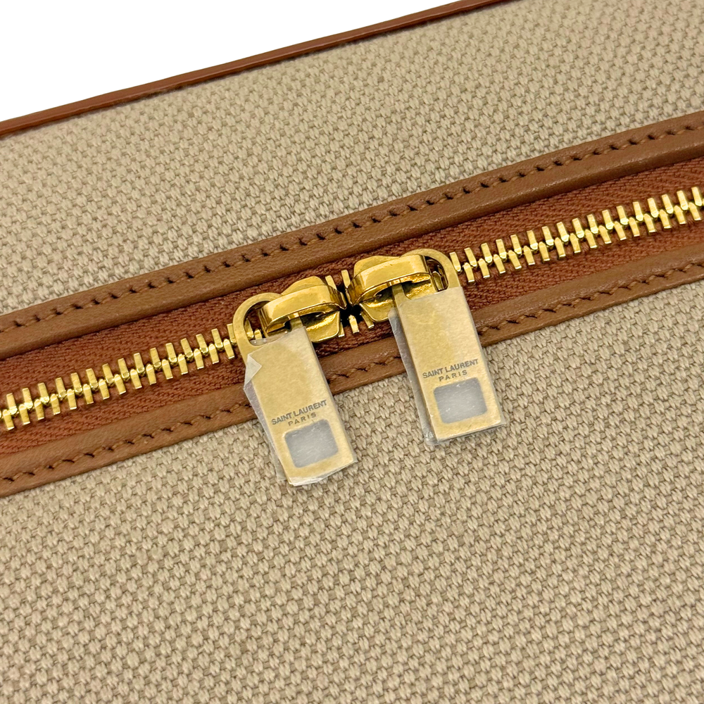 Gold zipper hardware on beige canvas vanity bag with brown leather edge trim