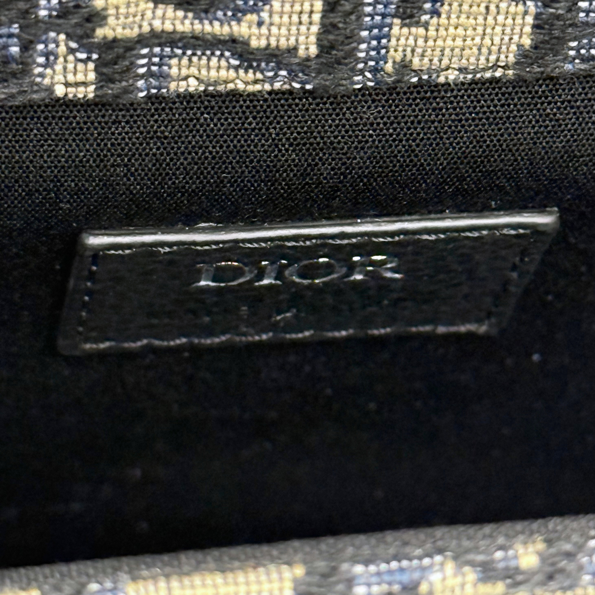 Black leather Dior brand tag on patterned canvas crossbody bag