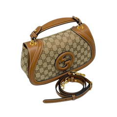 Gucci GG canvas shoulder bag with brown leather trim, gold clasp, and logo medallion