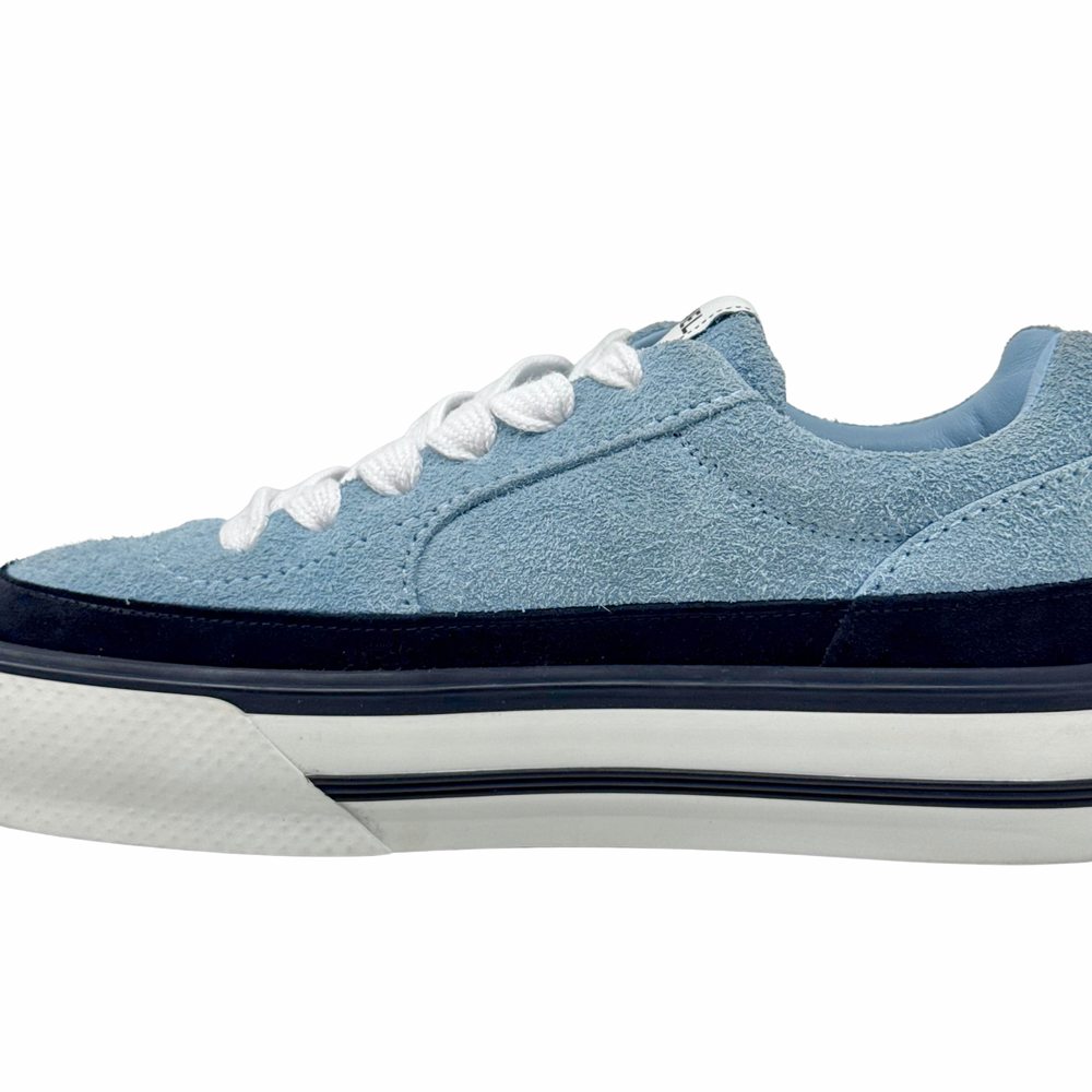 Close side view of blue suede sneaker with white laces and black trim