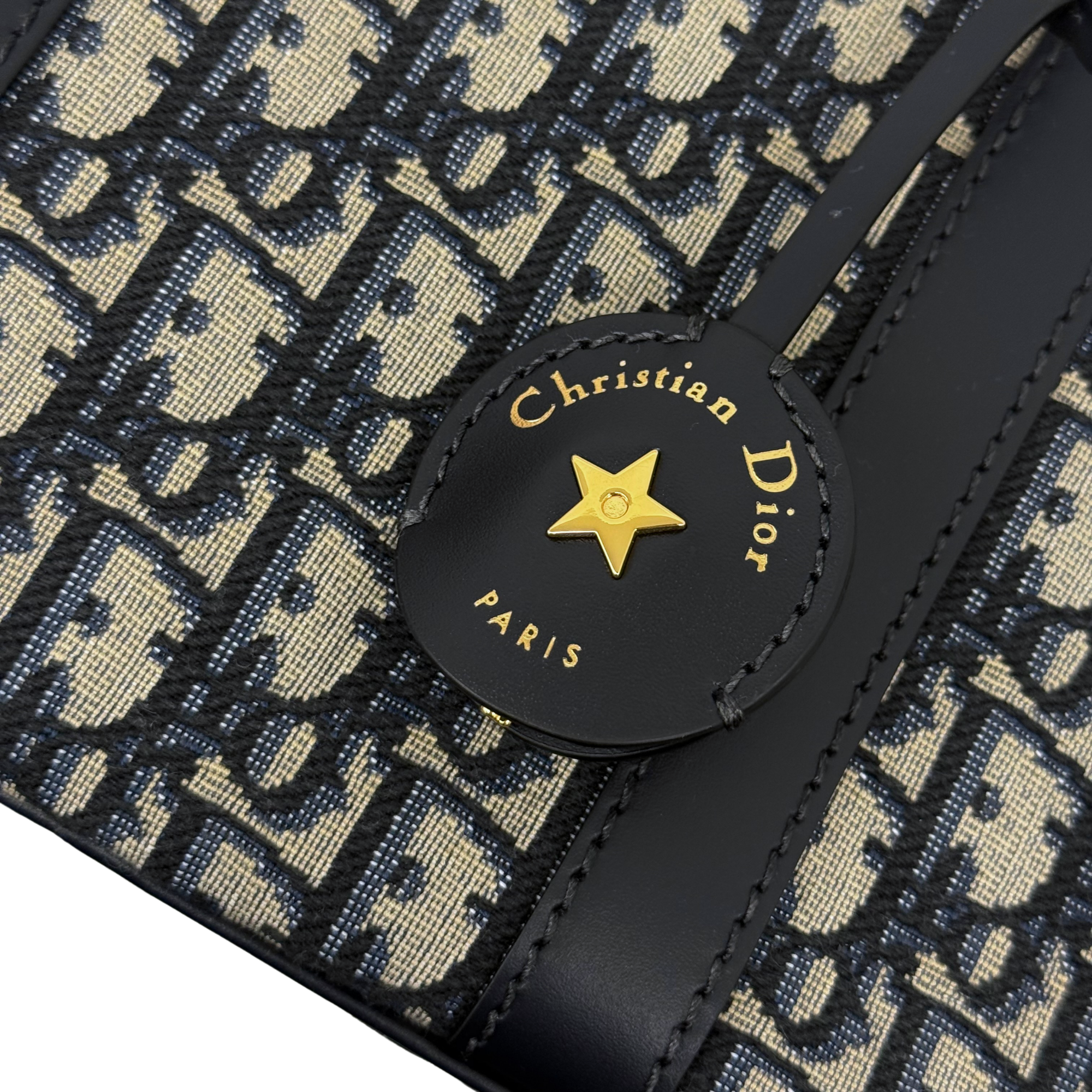 Christian Dior Paris charm on navy leather patch with star emblem on patterned bag
