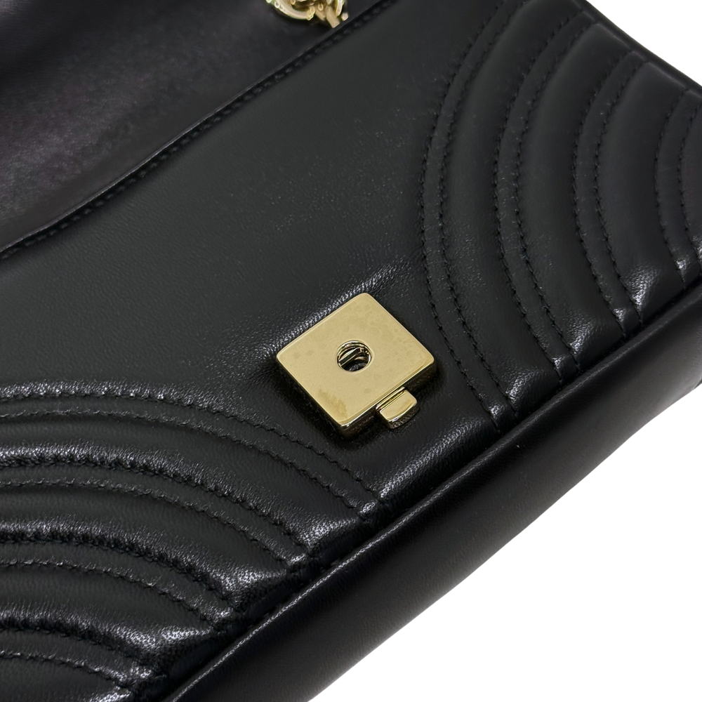 Gucci shoulder bag close-up of black quilted leather panel and gold snap hardware