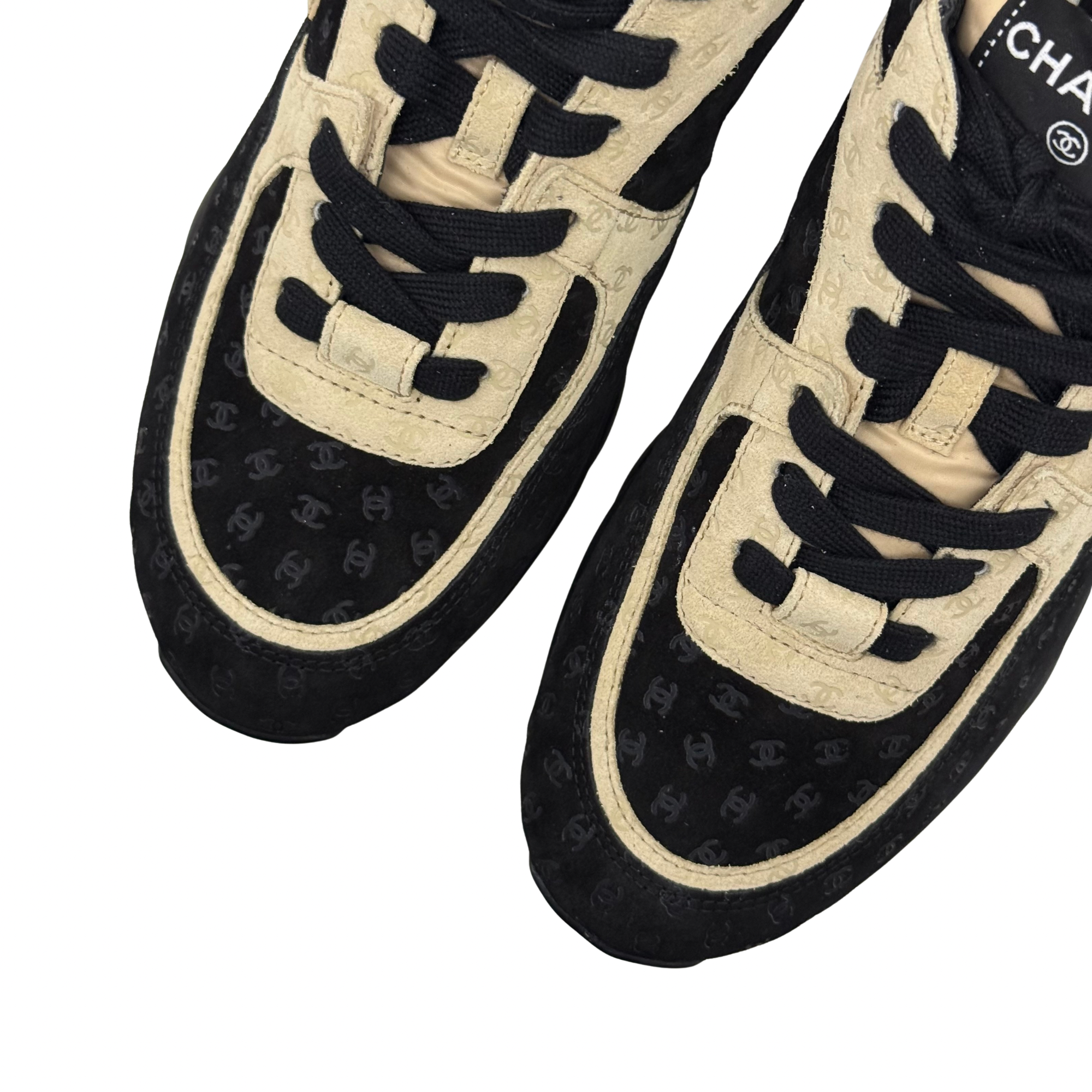 Black and beige Chanel sneakers close-up on toe and laces with branded tongue tab