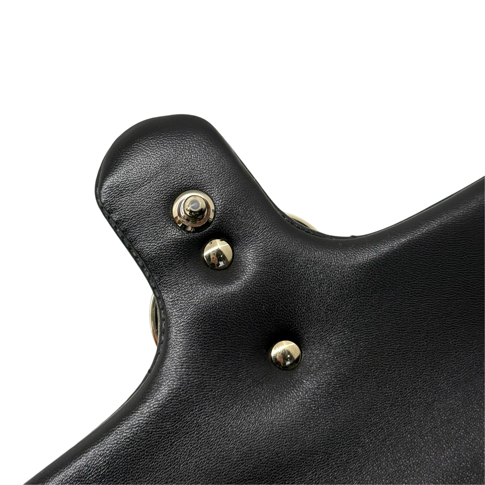 Gucci shoulder bag close-up of black leather flap with round gold snaps