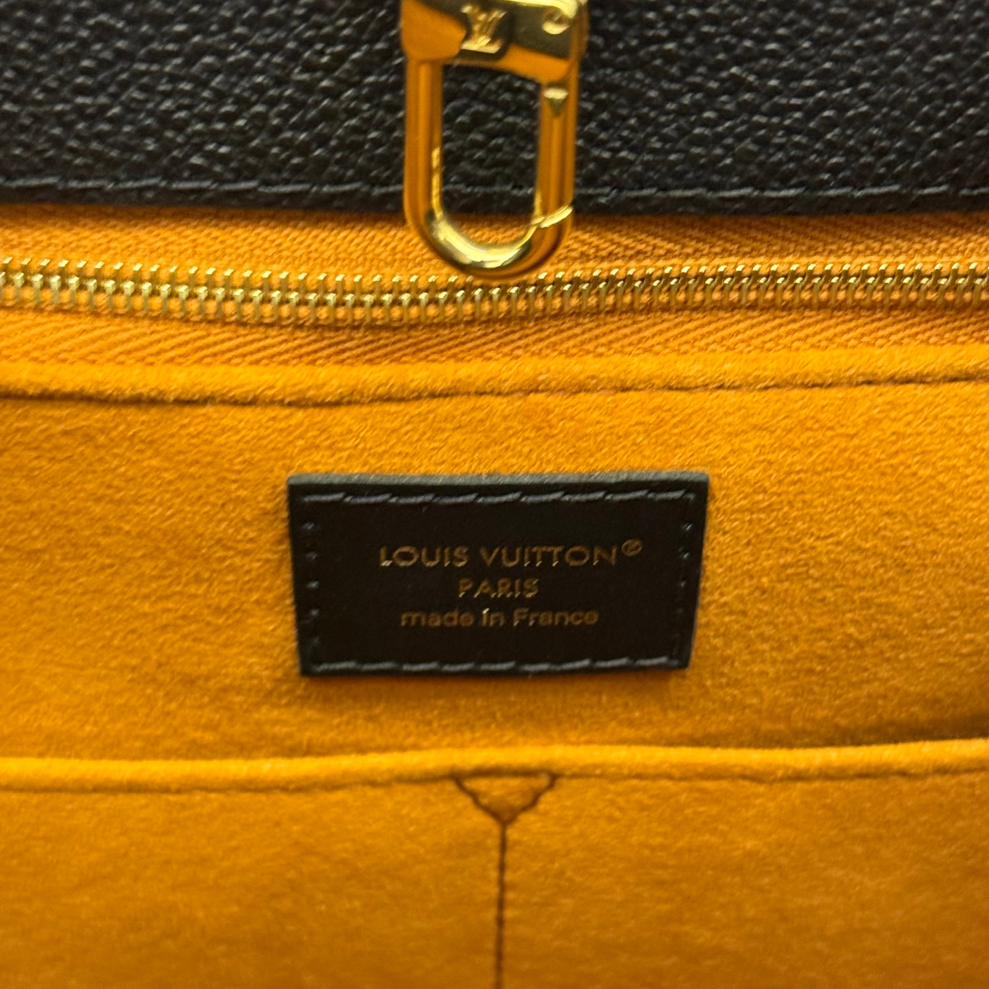 Louis Vuitton leather label with gold zipper and black fabric, close-up