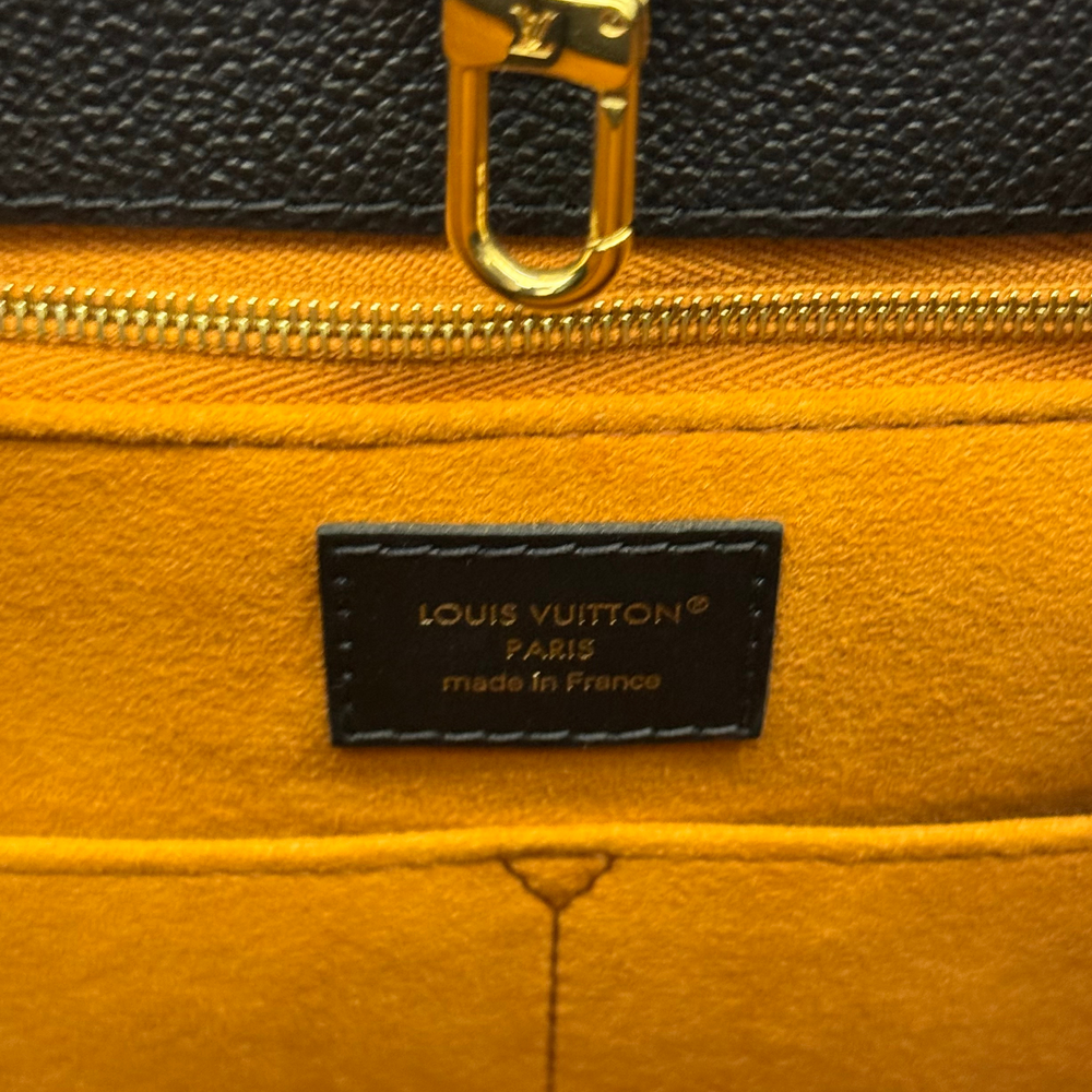 Louis Vuitton leather label with gold zipper and black fabric, close-up