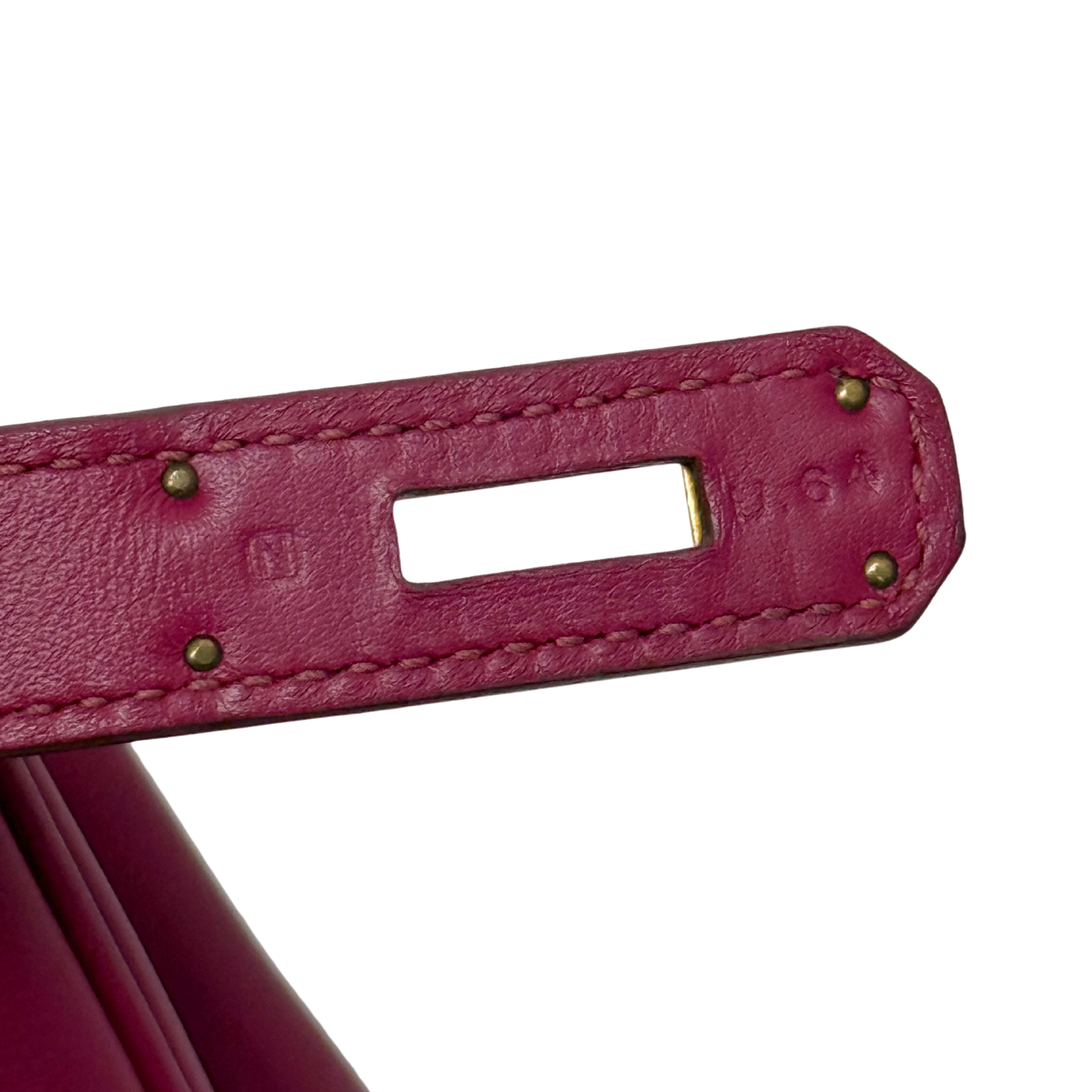 Magenta leather Birkin bag handle tab with gold studs and stitched detail