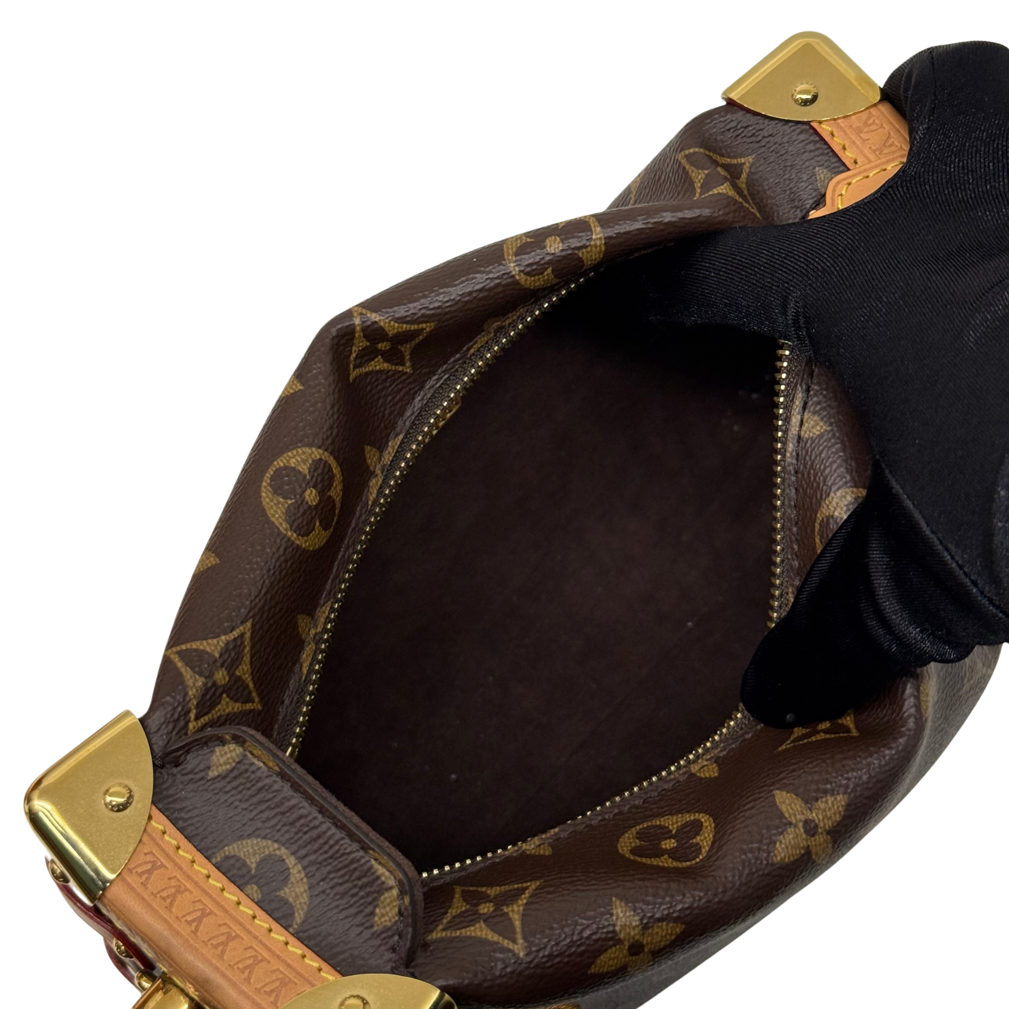 Interior of monogram crossbody bag with dark lining, open top, and gold zipper track