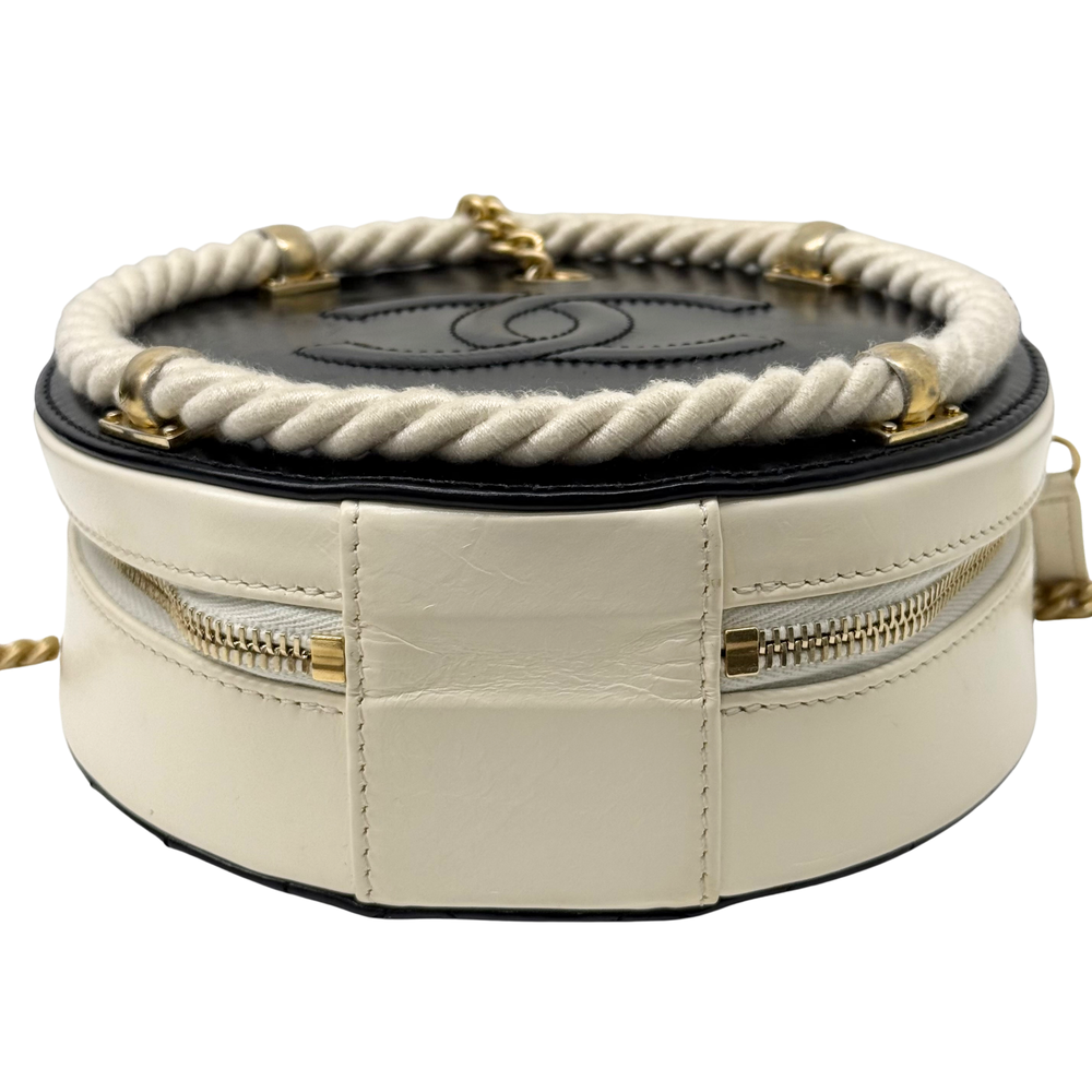 Top view of cream round bag with black base panel, braided trim, and gold hardware