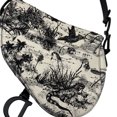 Christian Dior saddle bag side view with black-and-white toile scene and embroidered details.
