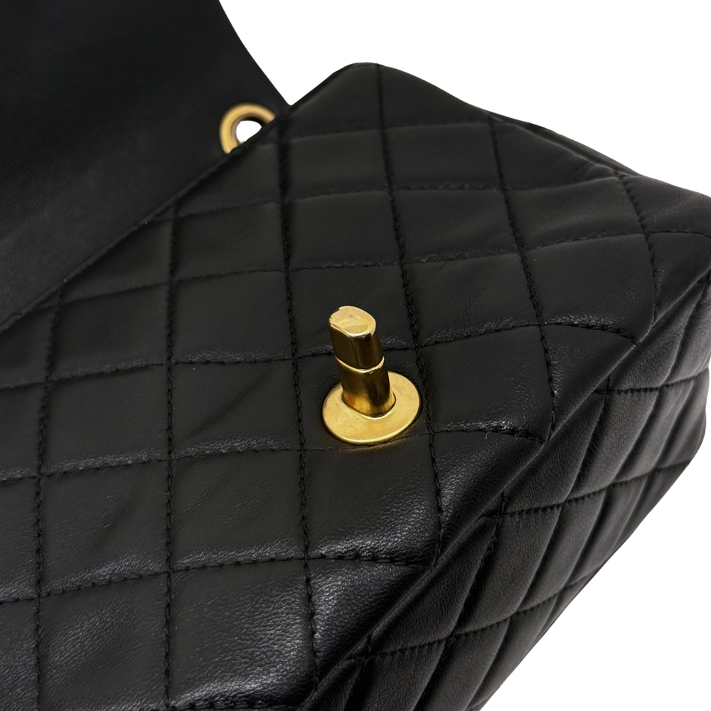 Pre-owned quilted shoulder bag flap close-up with black leather and gold snap button