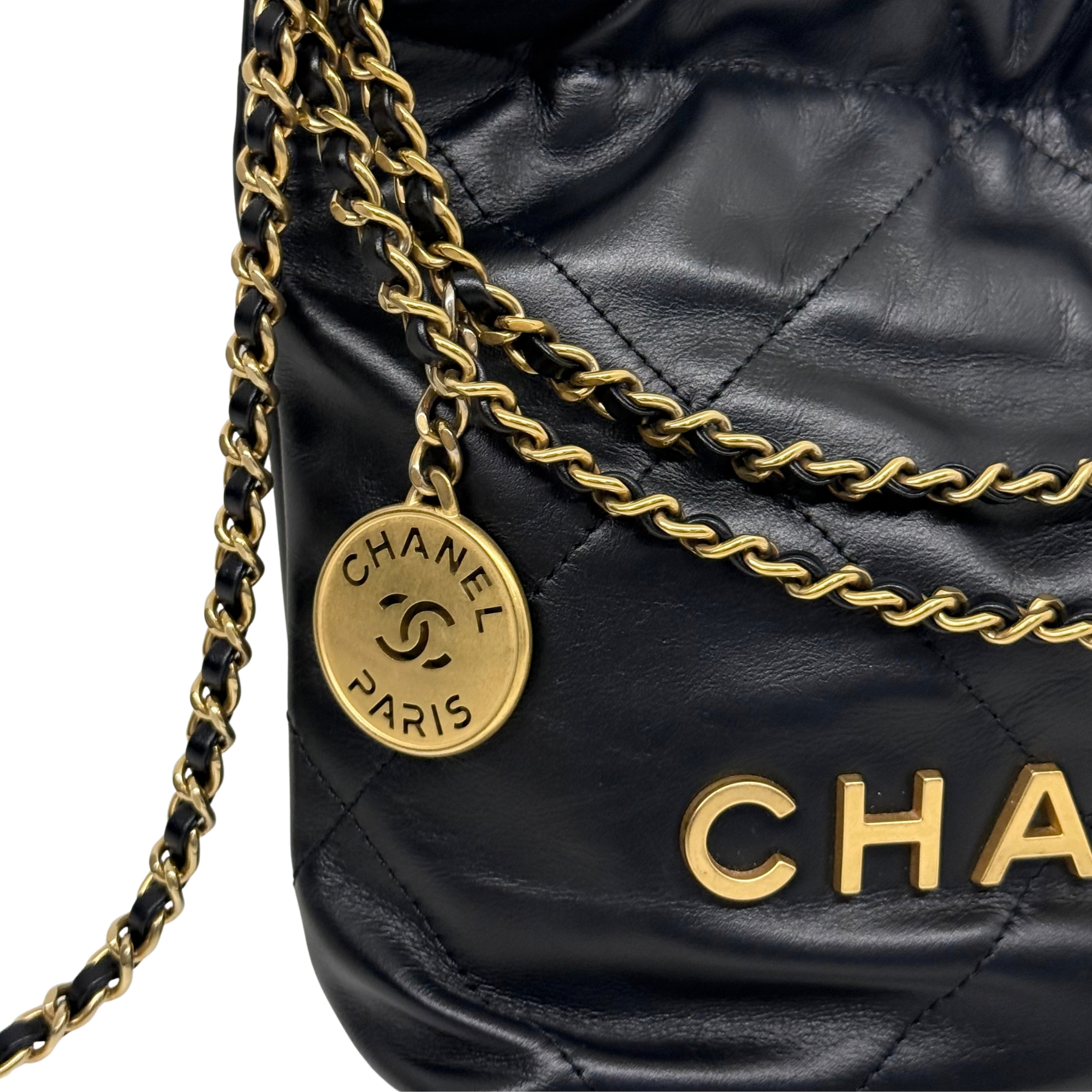 Black quilted mini crossbody bag with gold chain strap and round Chanel logo charm.