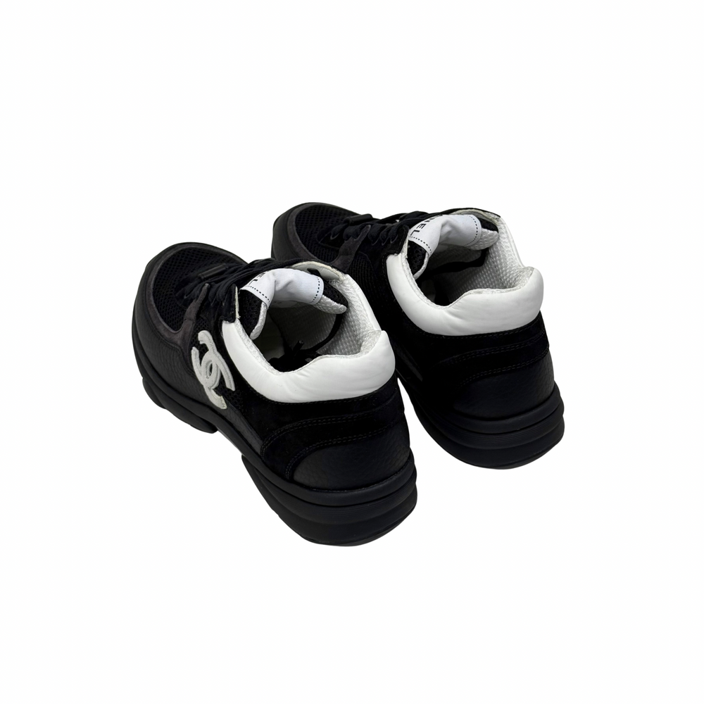 Black low-top sneakers with white inner lining and logo detail on heel.