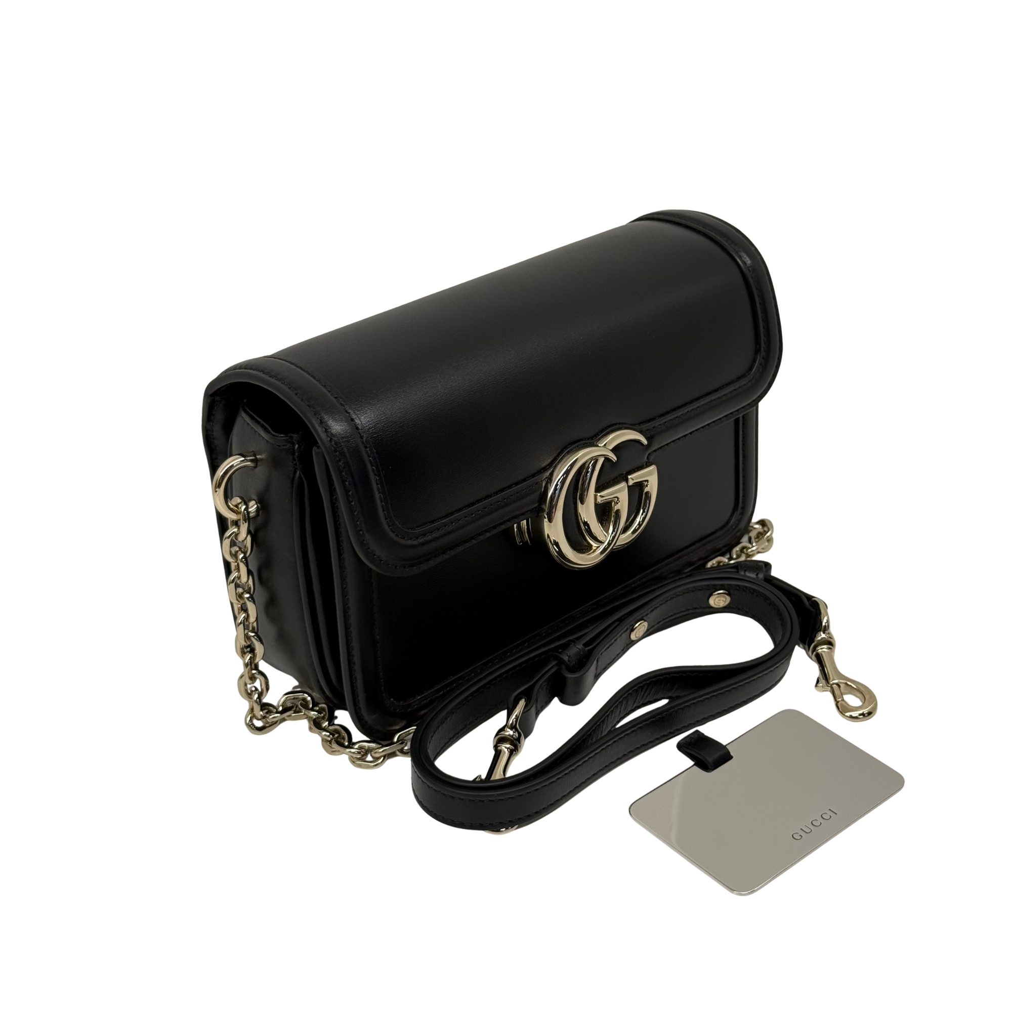 Black leather mini shoulder bag with gold-tone GG clasp, chain strap, and tag