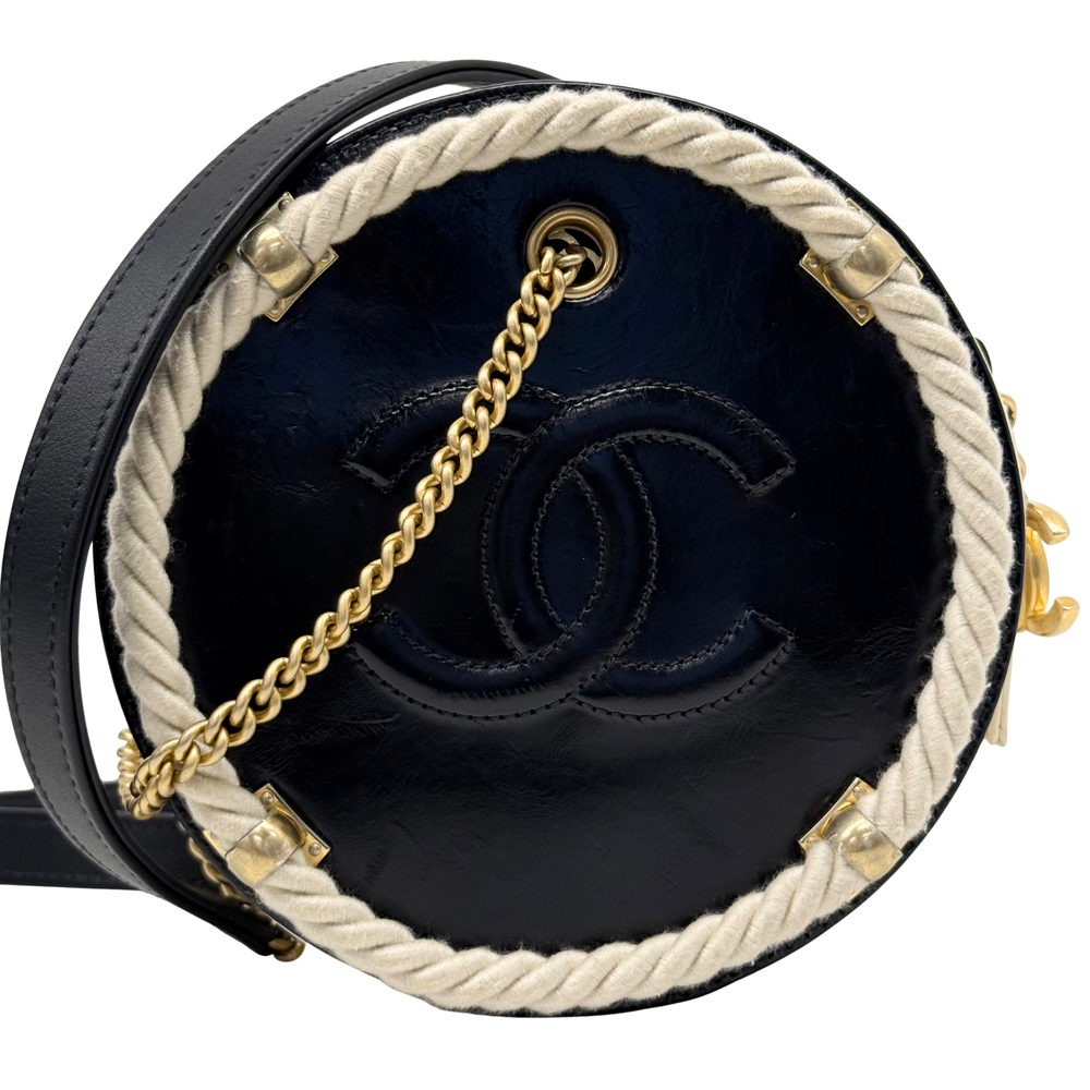 Round Chanel bag with black exterior, navy interior, CC logo, and gold chain strap.