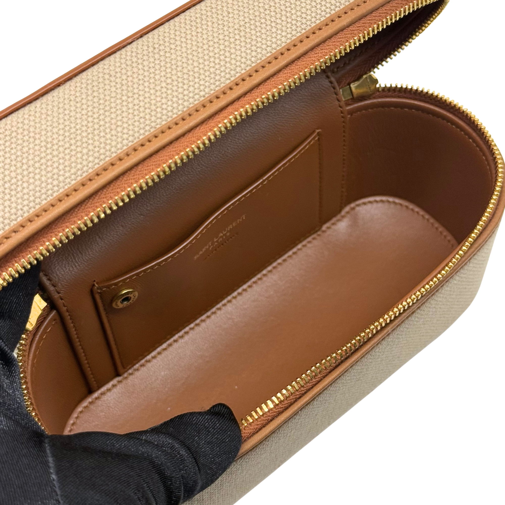Interior view of beige vanity bag with brown lining and gold zipper track