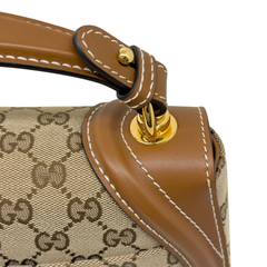 Close-up of tan leather tab with gold-tone ring and snap detail