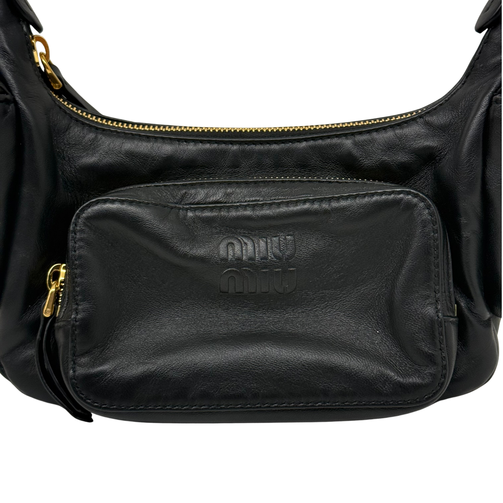 Black leather shoulder bag front pocket with embossed logo and gold zipper pull