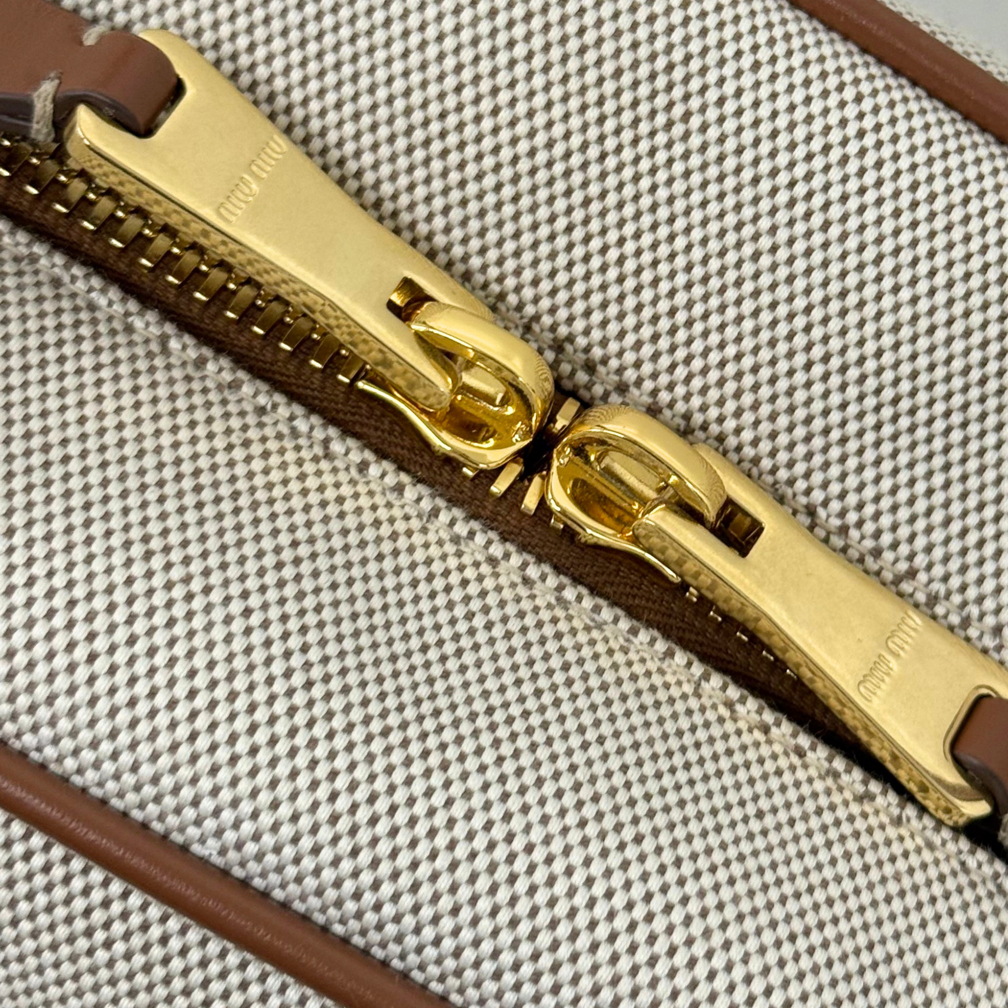Miu Miu zipper detail with gold-tone hardware on canvas