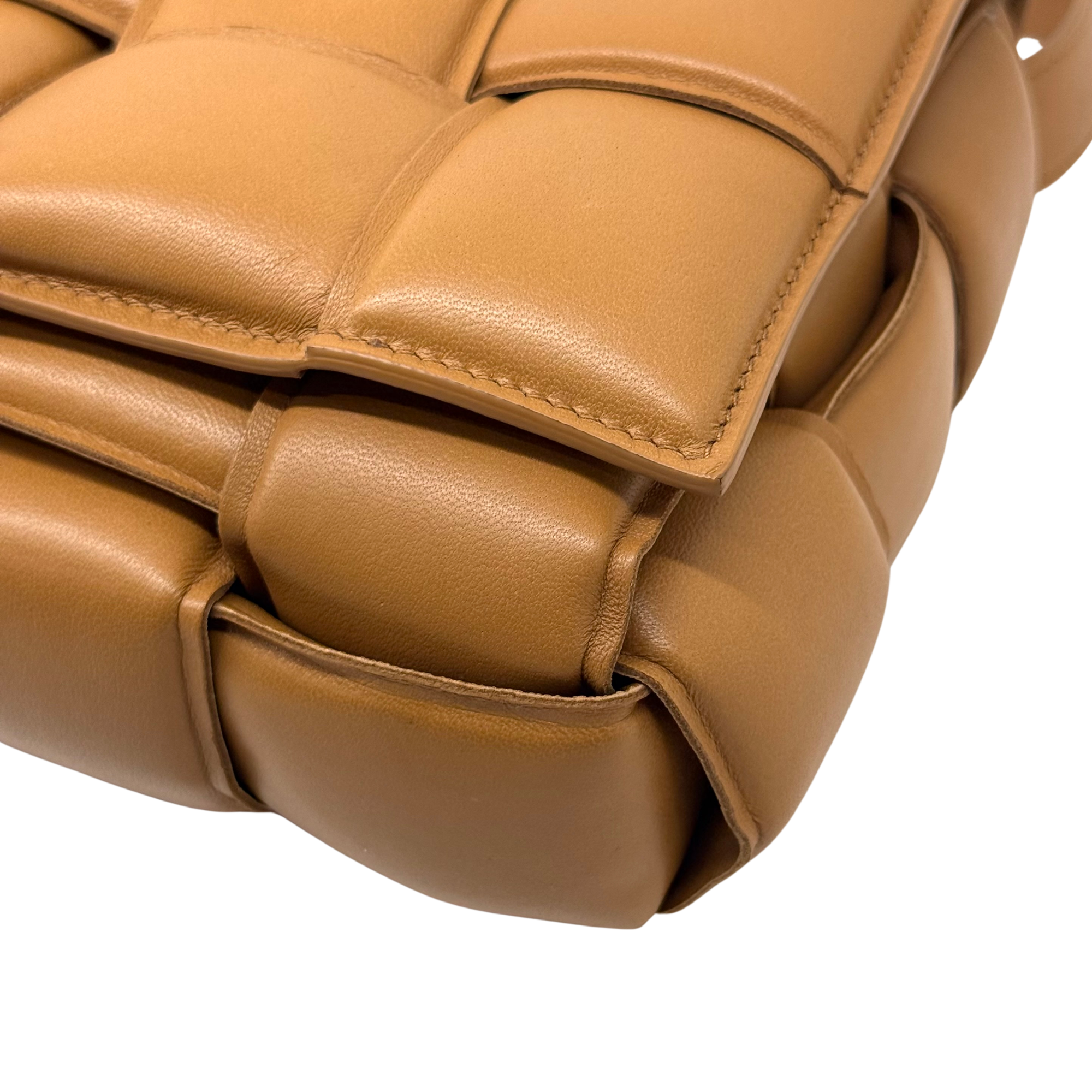 Tan leather bag corner with stitched flap detail and rounded padded edge