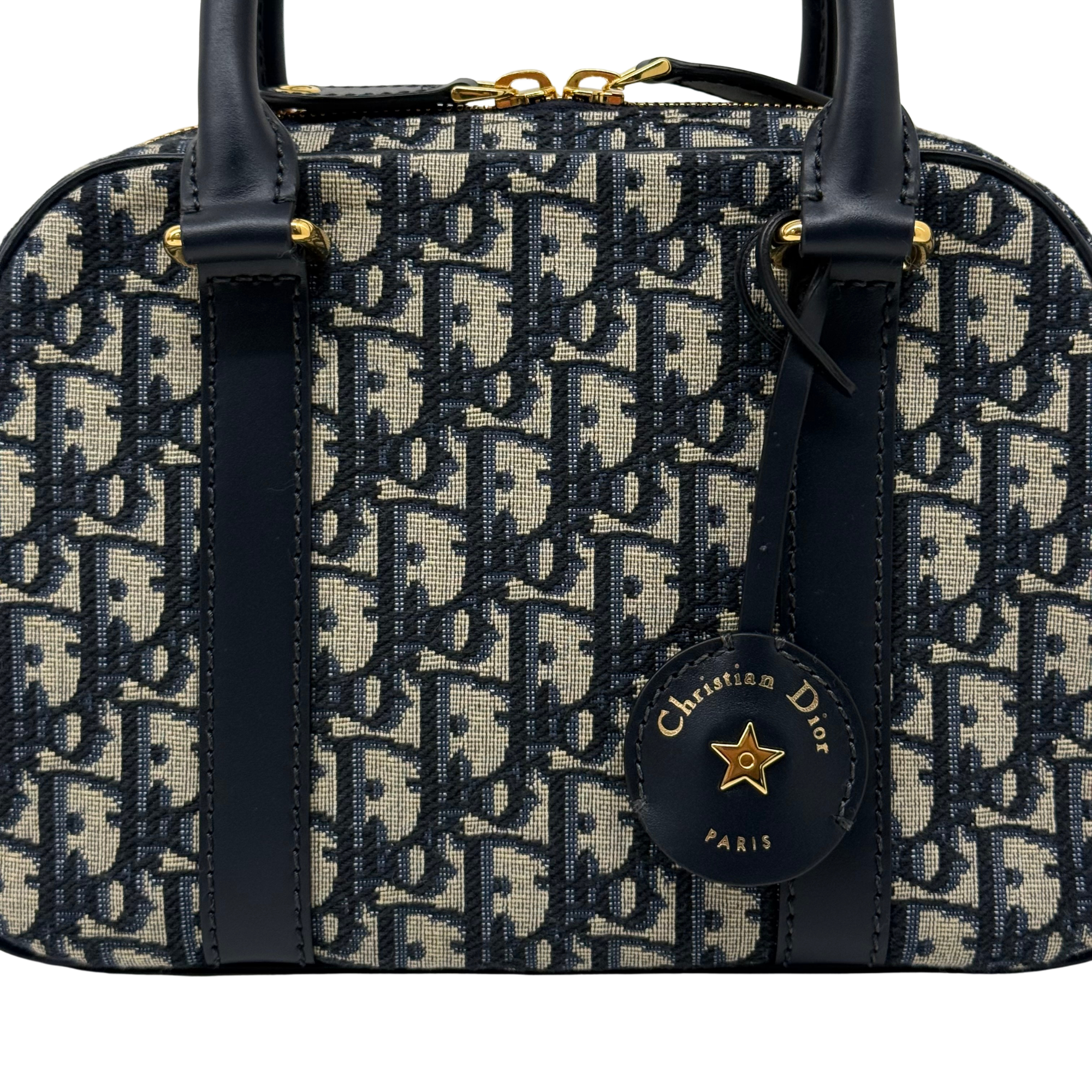 Dior monogram duffel bag with navy leather straps and front logo charm, gold accents