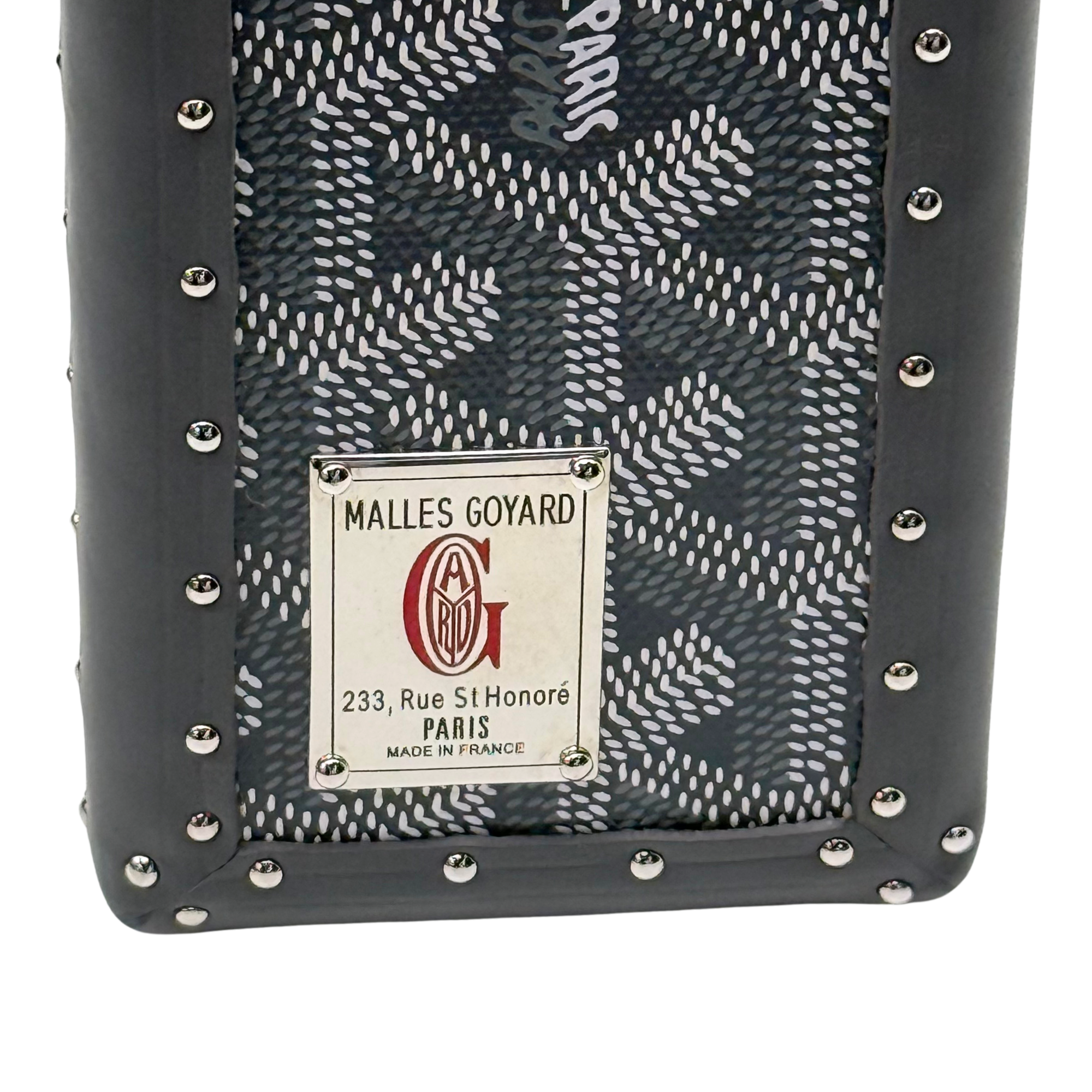 Goyard trunk interior-side label on patterned fabric with studded dark frame edges