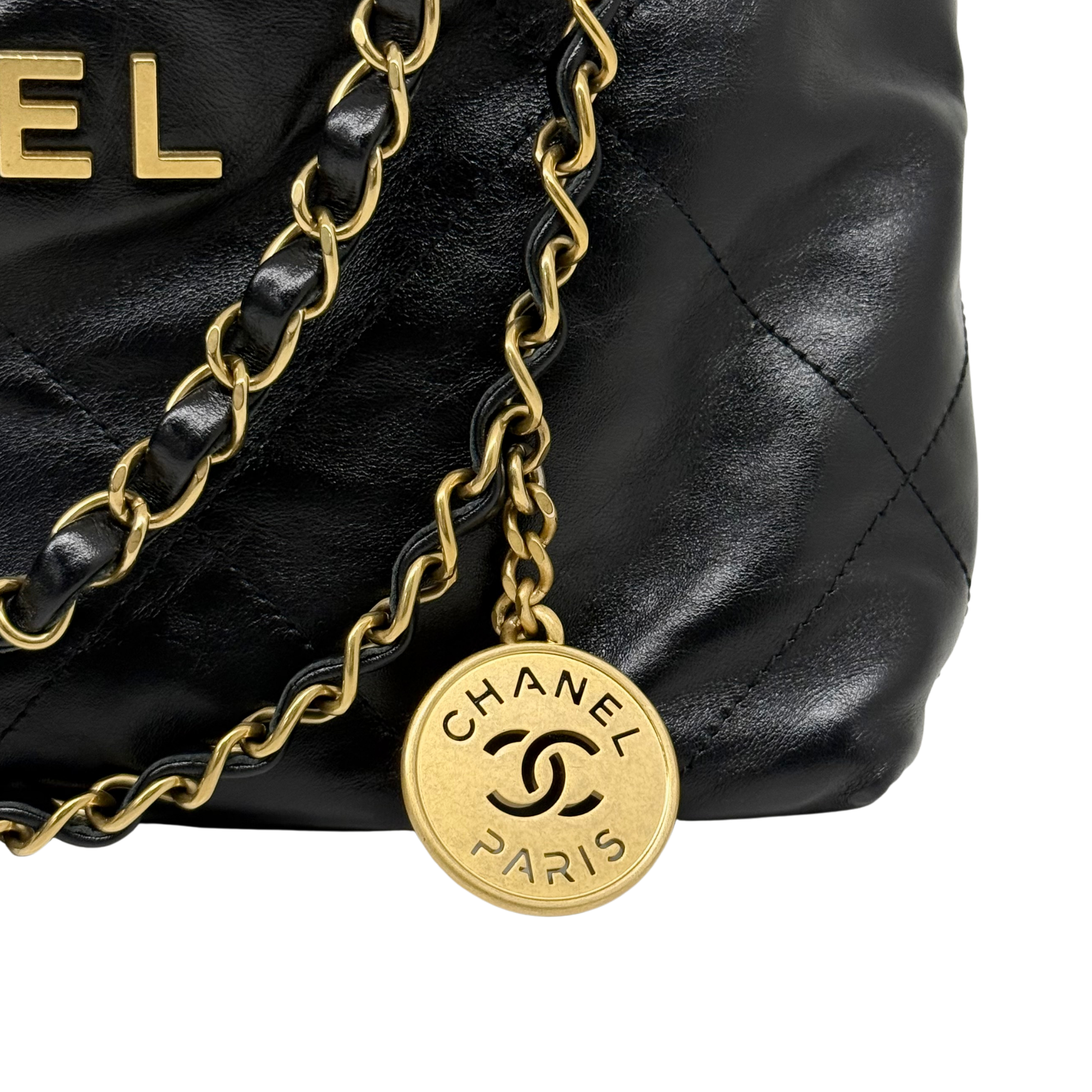 Black leather bag with gold chain and round CHANEL PARIS charm at center
