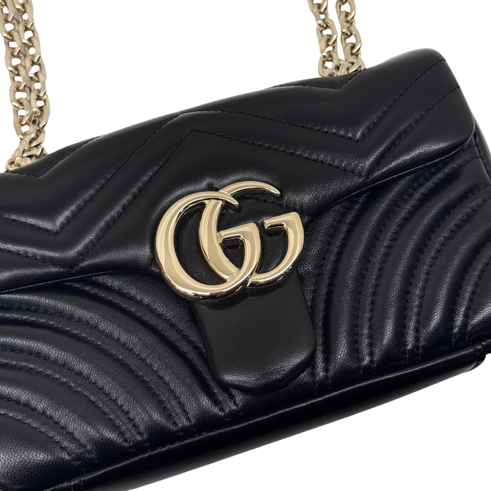 Gucci shoulder bag close-up of gold interlocking double-G logo on black quilted flap