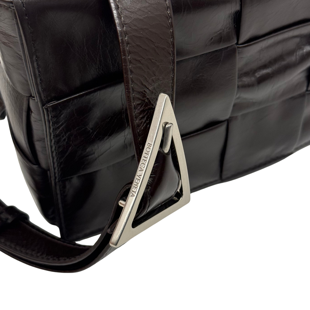 Quilted dark bag with silver metal logo plate and adjustable shoulder strap