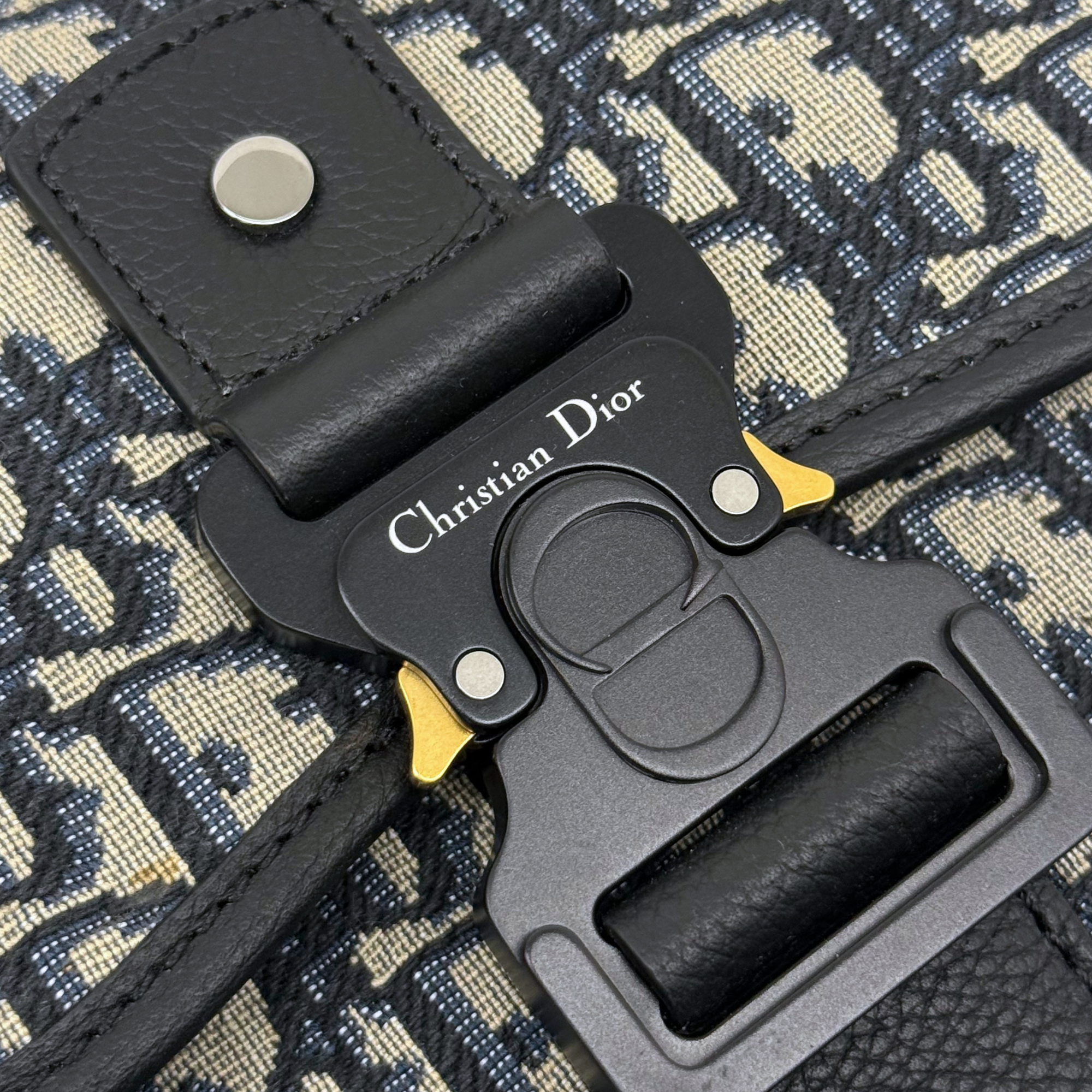 Christian Dior engraved clasp with gold accents on patterned canvas crossbody bag