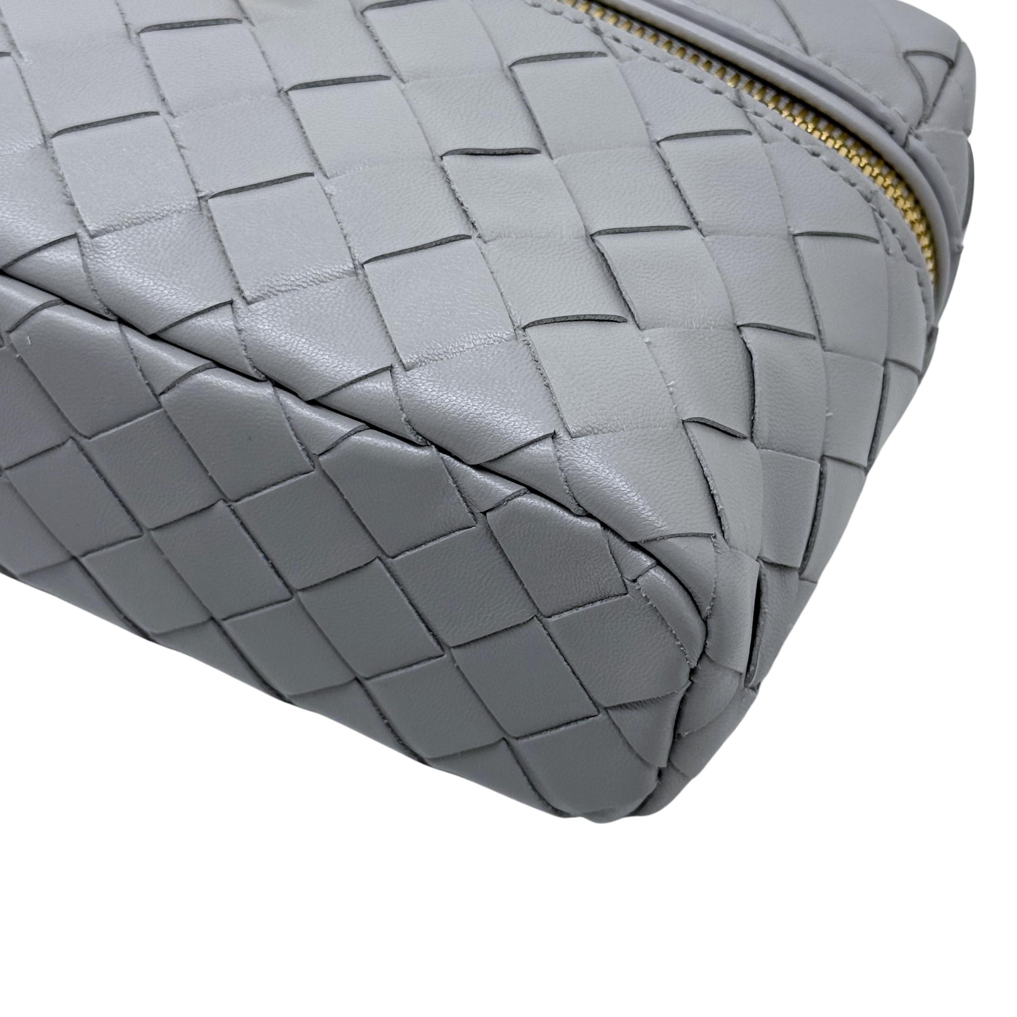 Bottega Veneta gray woven leather side panel with gold zipper edge and structured corners.