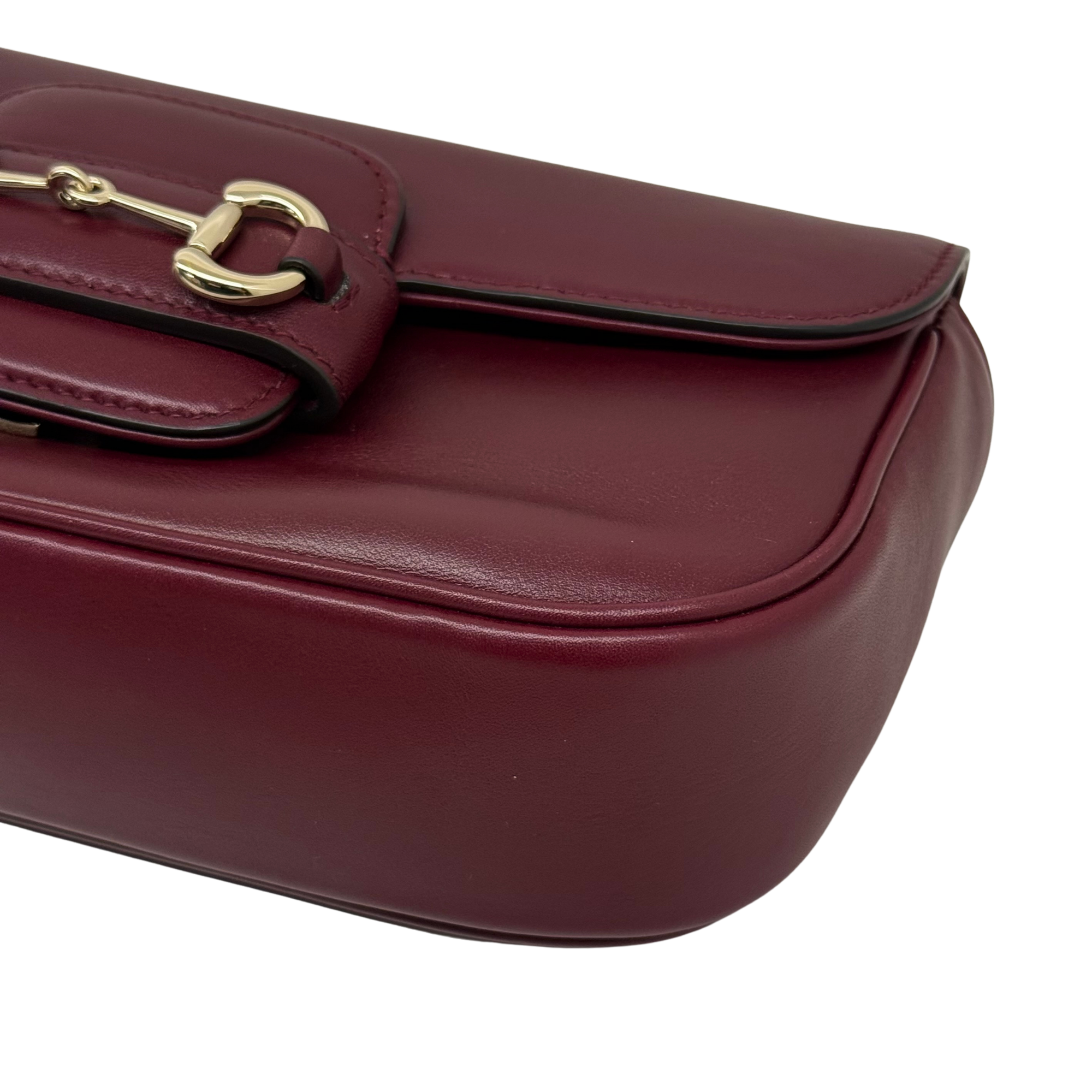 Maroon leather mini bag corner detail with buckle clasp and stitched edge