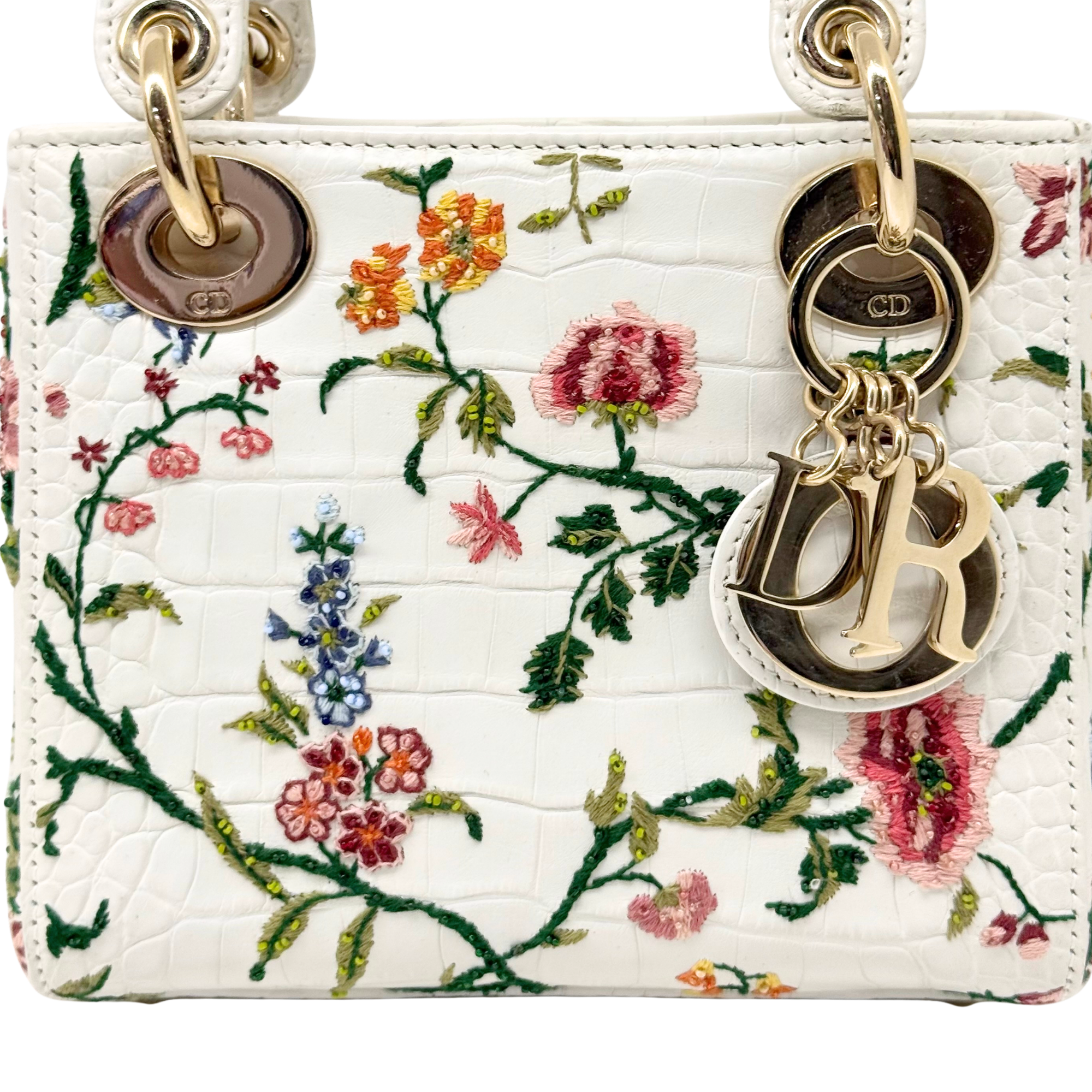 White floral mini handbag close-up with quilted texture and gold chain charms