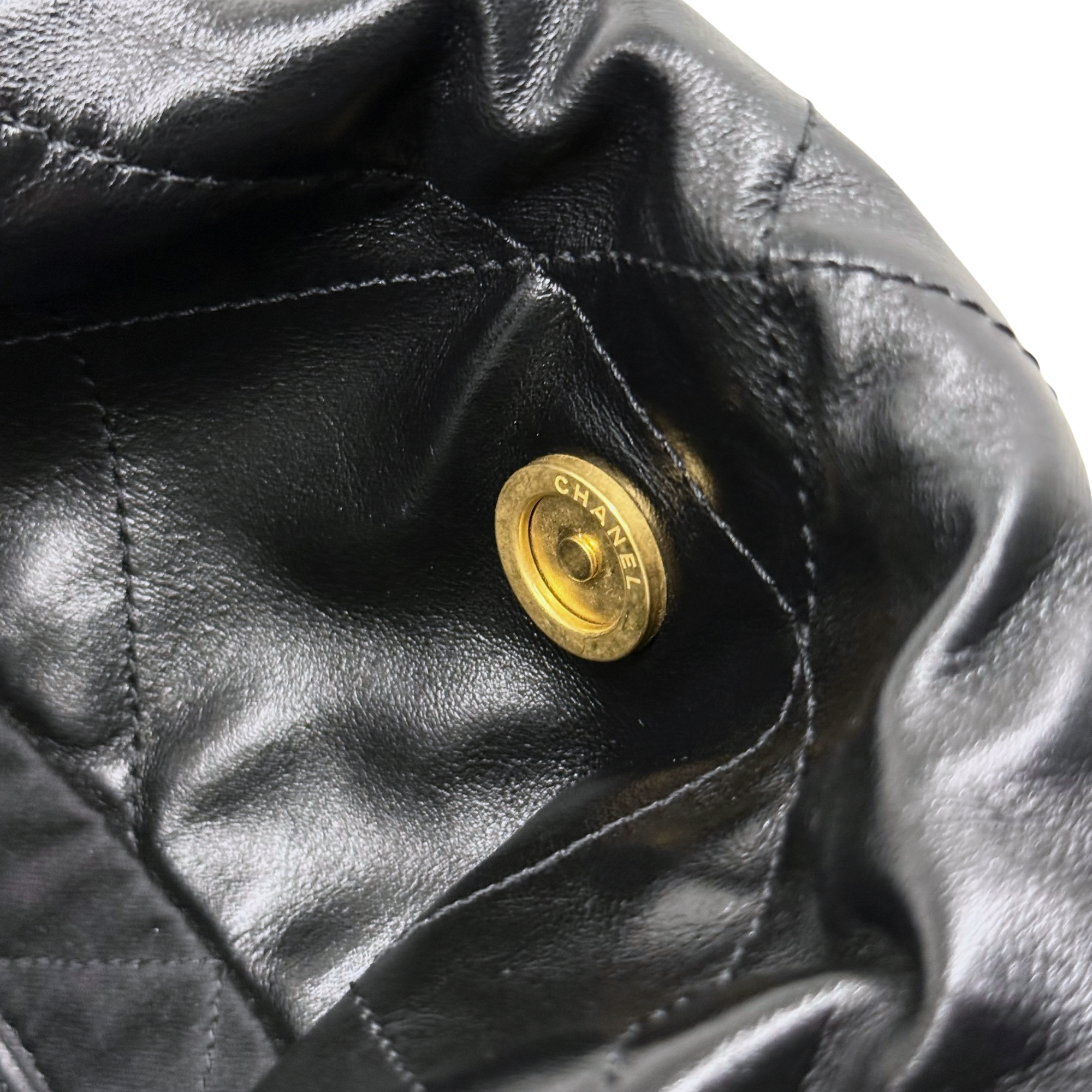 Black leather with round gold CHANEL snap button and quilted seam detail