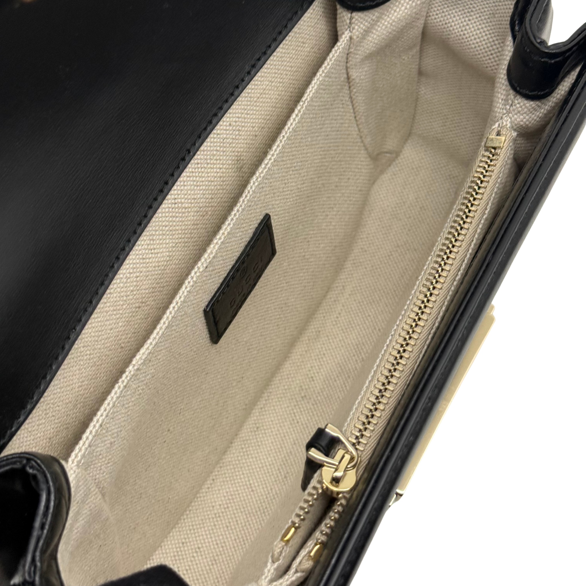 Beige fabric-lined interior with zipper and leather logo patch