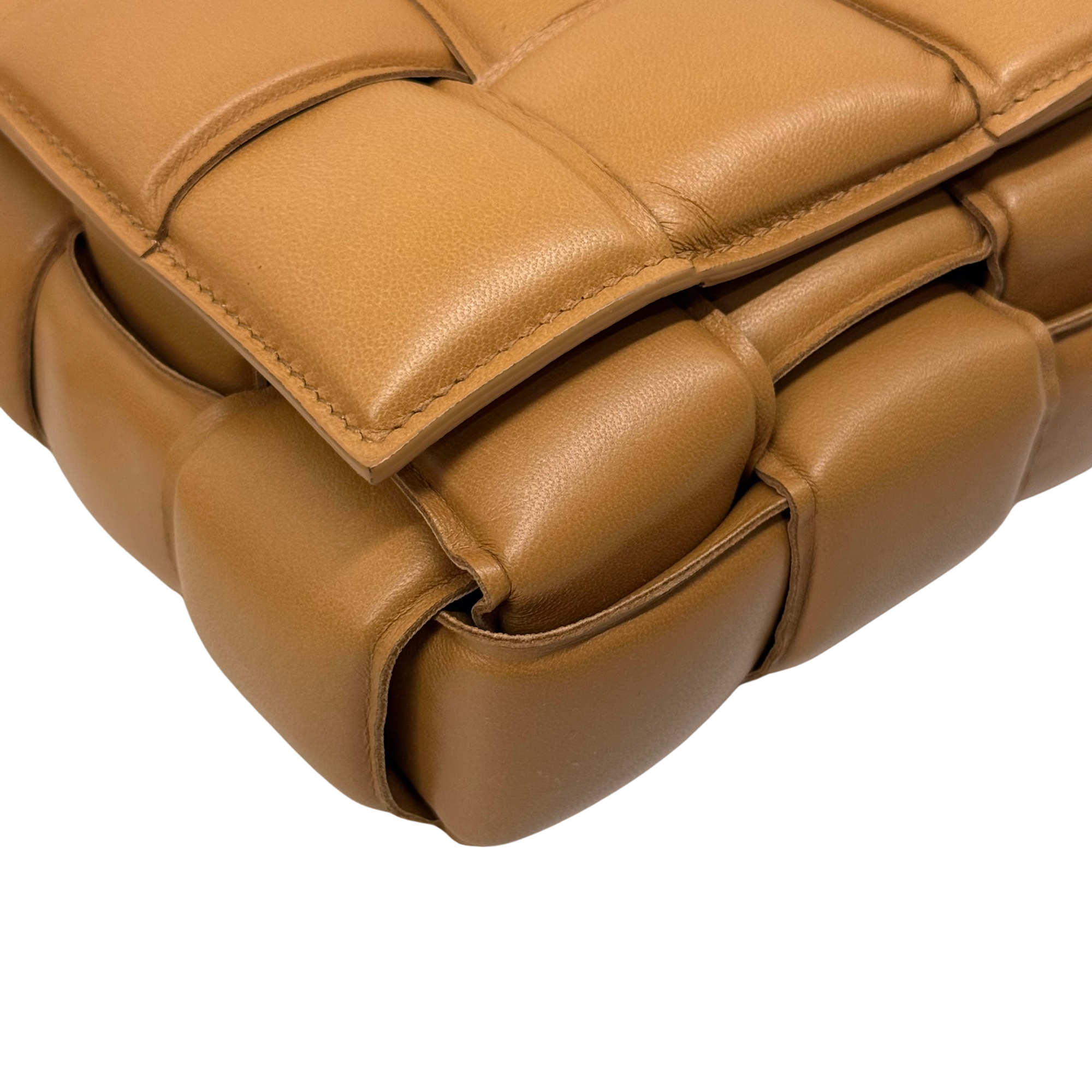 Tan quilted leather bag with strap attachment and stitched padded corner