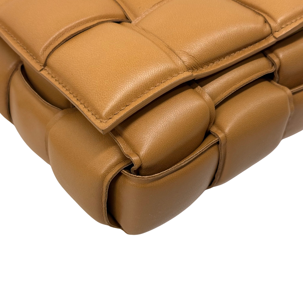 Tan quilted leather bag with strap attachment and stitched padded corner