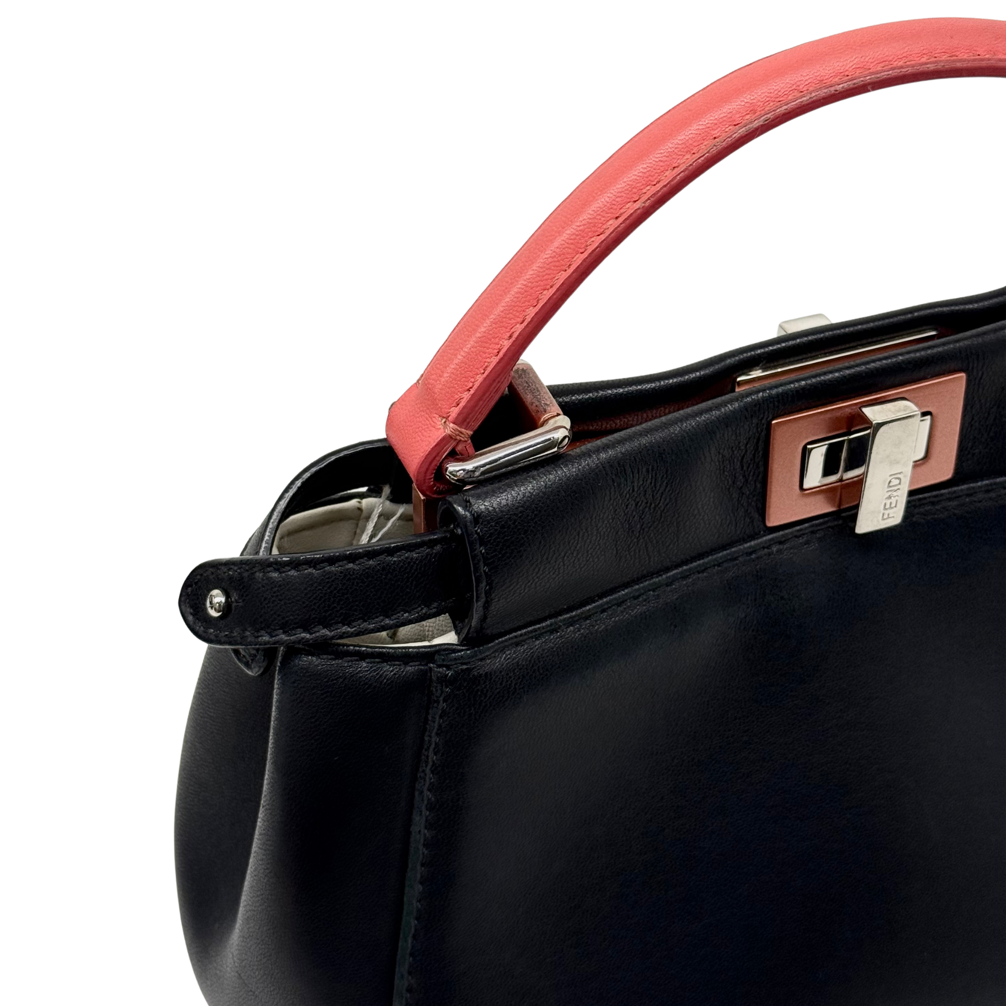 Pre-owned Fendi black leather handbag close-up, coral-pink handle strap and logo plate