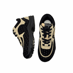 Black and beige Chanel low-top sneakers with lace-up closure and chunky rubber sole