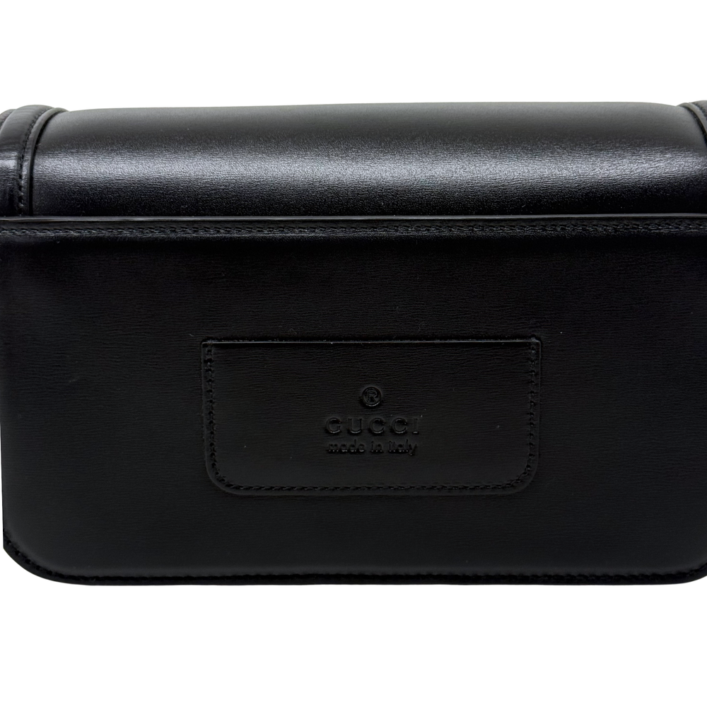 Black leather bag with embossed logo patch on the front flap