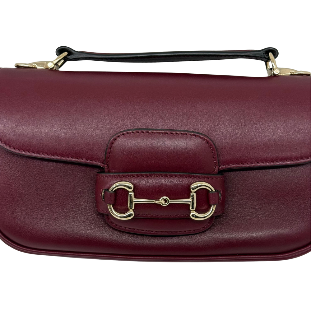 Maroon leather mini bag close-up of front buckle clasp hardware