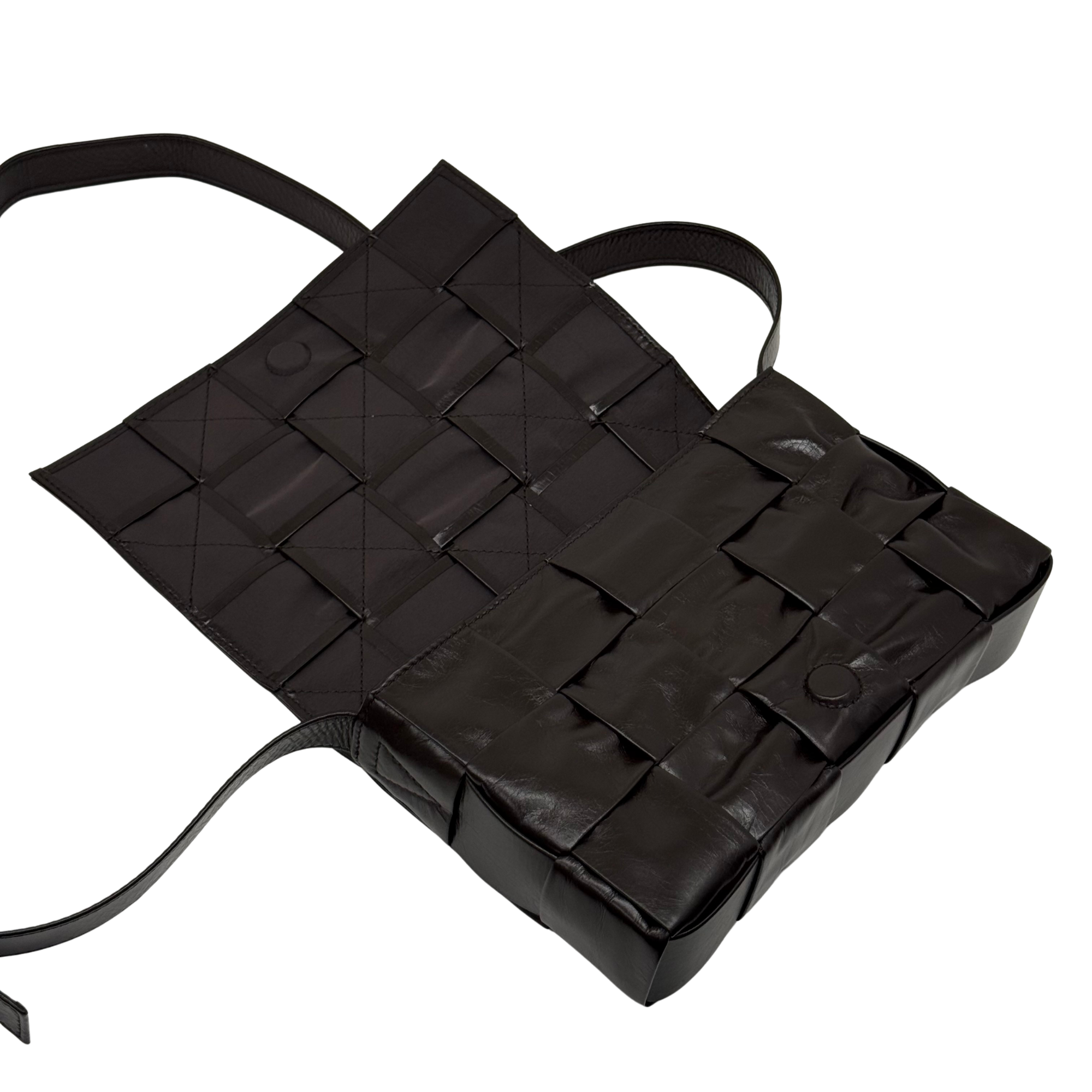 Quilted dark bag with open top and two handles, showing inner compartments