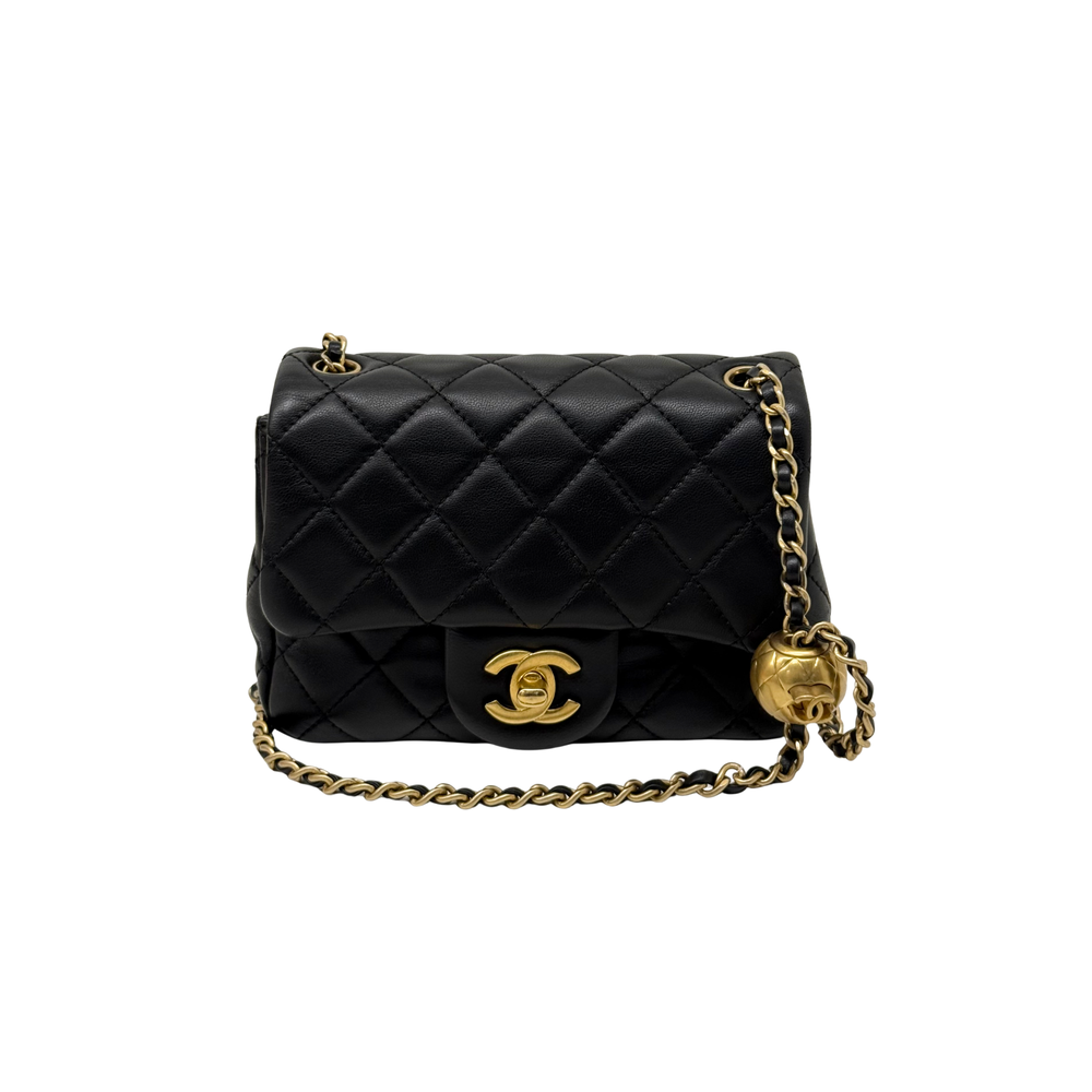 Black quilted shoulder bag with top flap, gold CC clasp, and gold chain tassel pull
