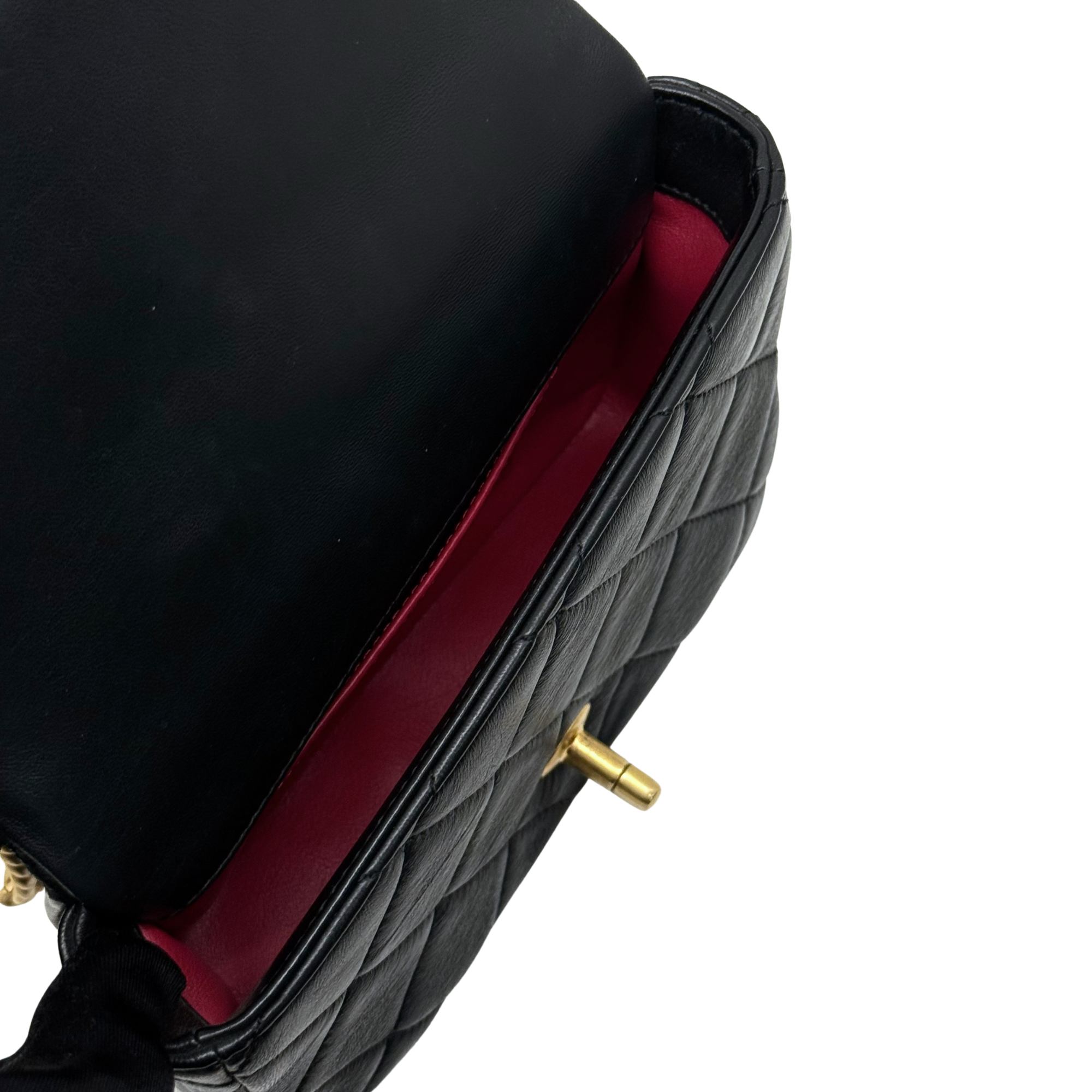 Black quilted flap bag with red fabric lining glimpse and gold-tone chain strap