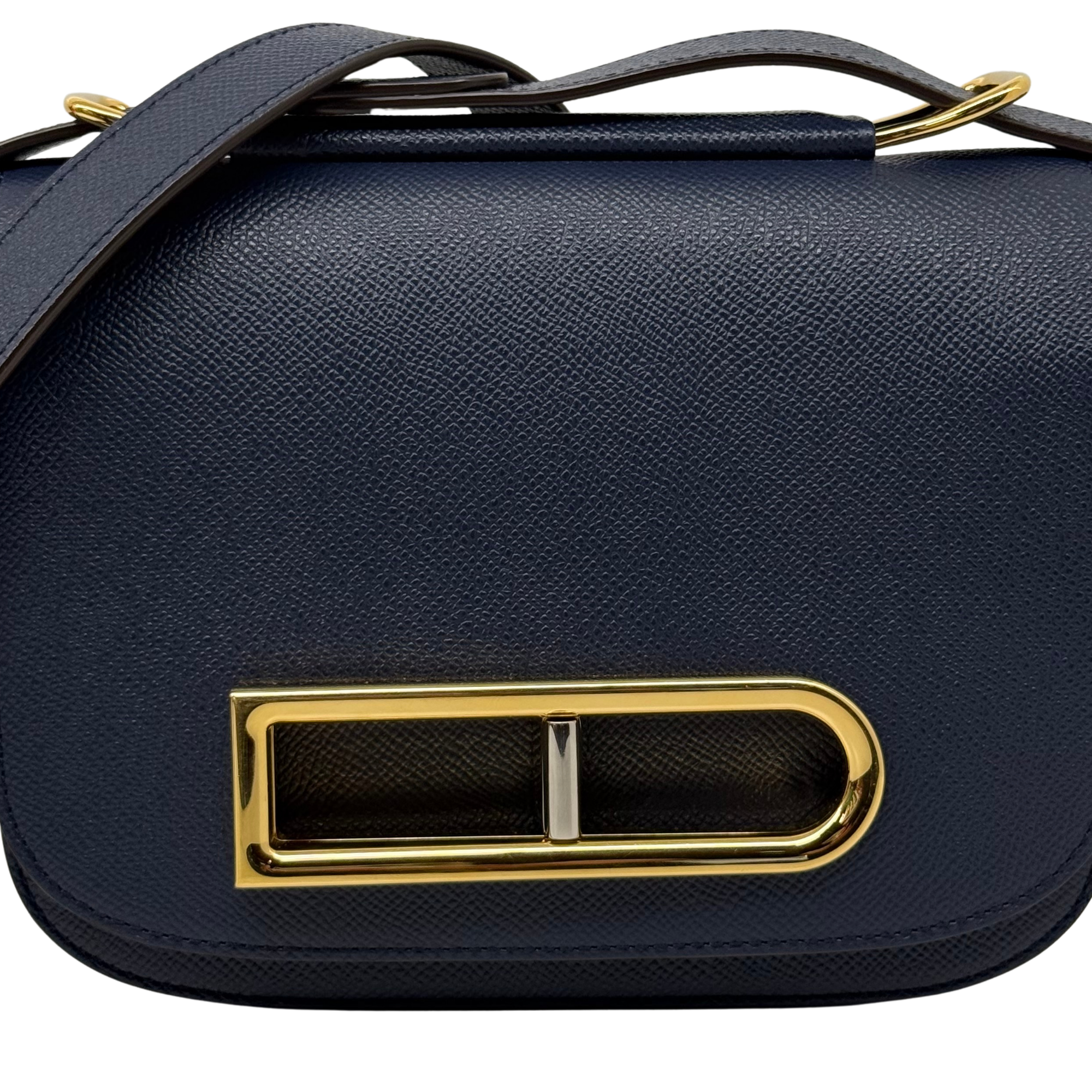 Navy leather flap satchel close-up of gold front clasp and textured grain