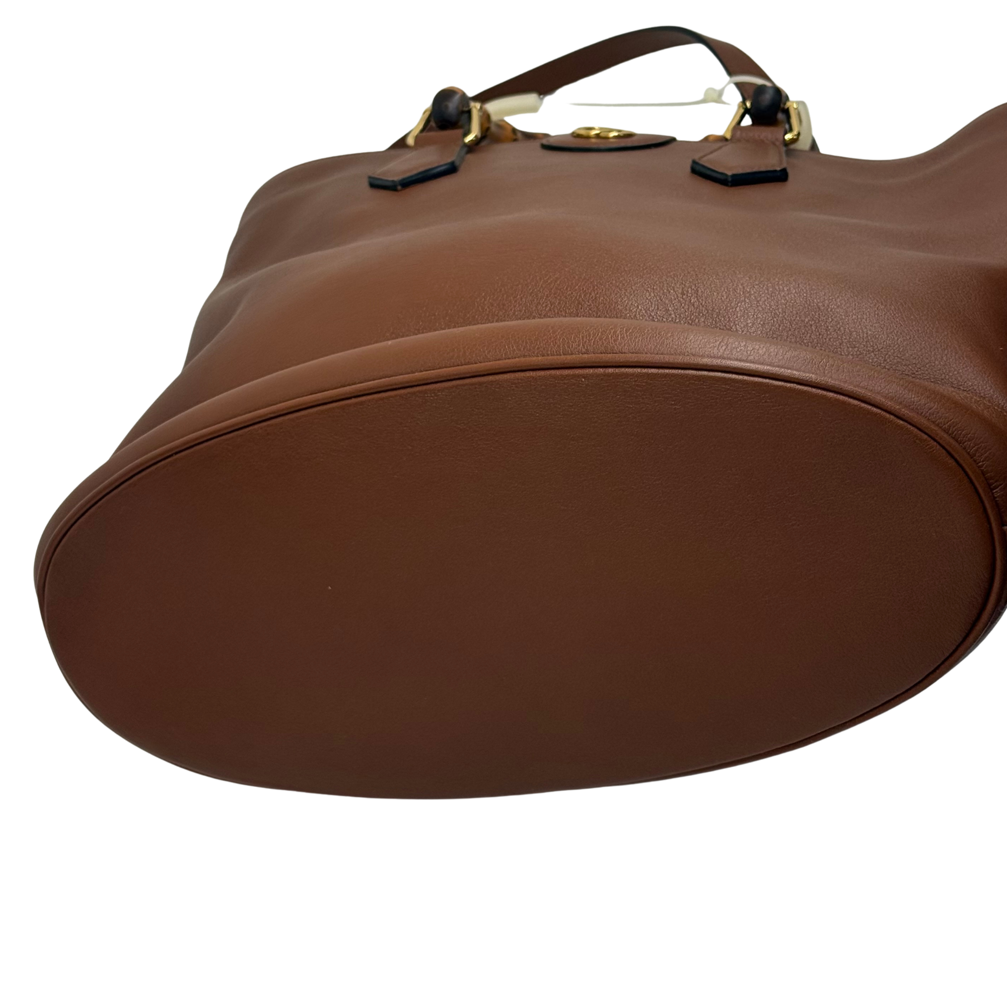 Brown leather top with structured curve, bamboo-style handles, and gold-tone rings
